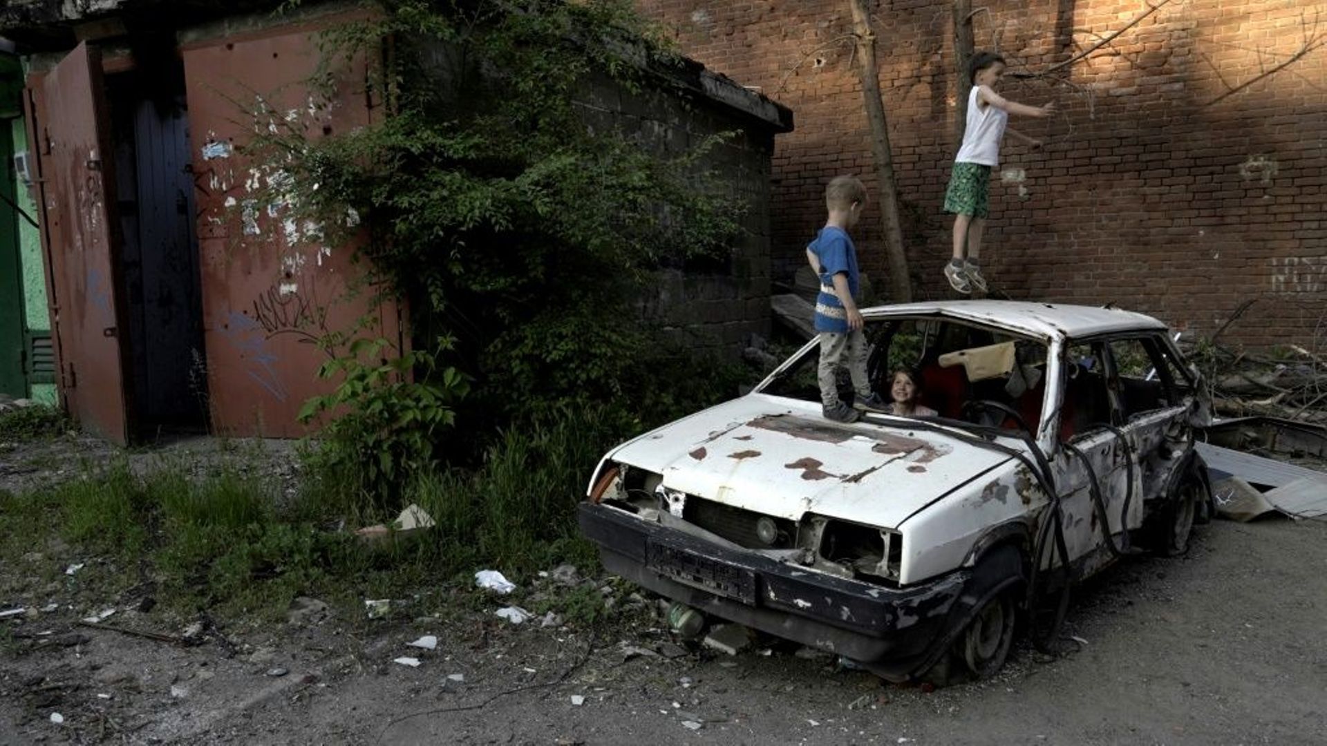 Des enfants jouent sur une carcasse de voiture le 29 mai 2022 à Marioupol, Ukraine