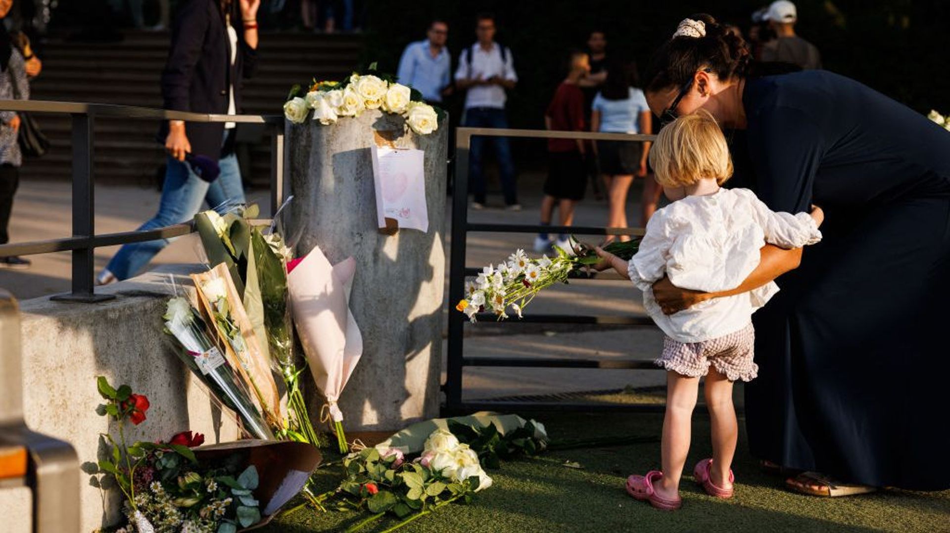 Une femme et sa fille déposent des fleurs au parc pour enfants du parc Paquier, où une attaque au couteau a eu lieu, le 8 juin 2023 à Annecy, France. Plusieurs personnes, dont quatre jeunes enfants, ont été blessées lors d’une attaque au couteau dans une
