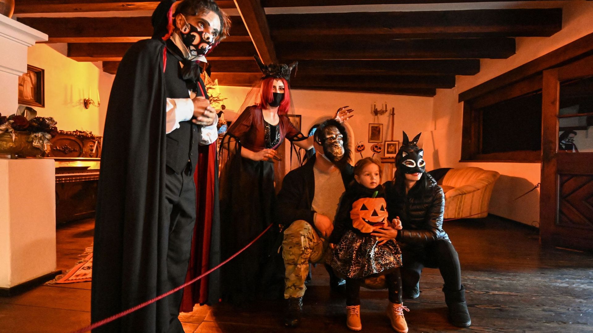 Des visiteurs posent à côté d'acteurs masqués se faisant passer pour Dracula et une de ses épouses maléfiques lors d'une visite spéciale du château de Bran organisée pour Halloween dans le village de Bran le 31 octobre 2020. 