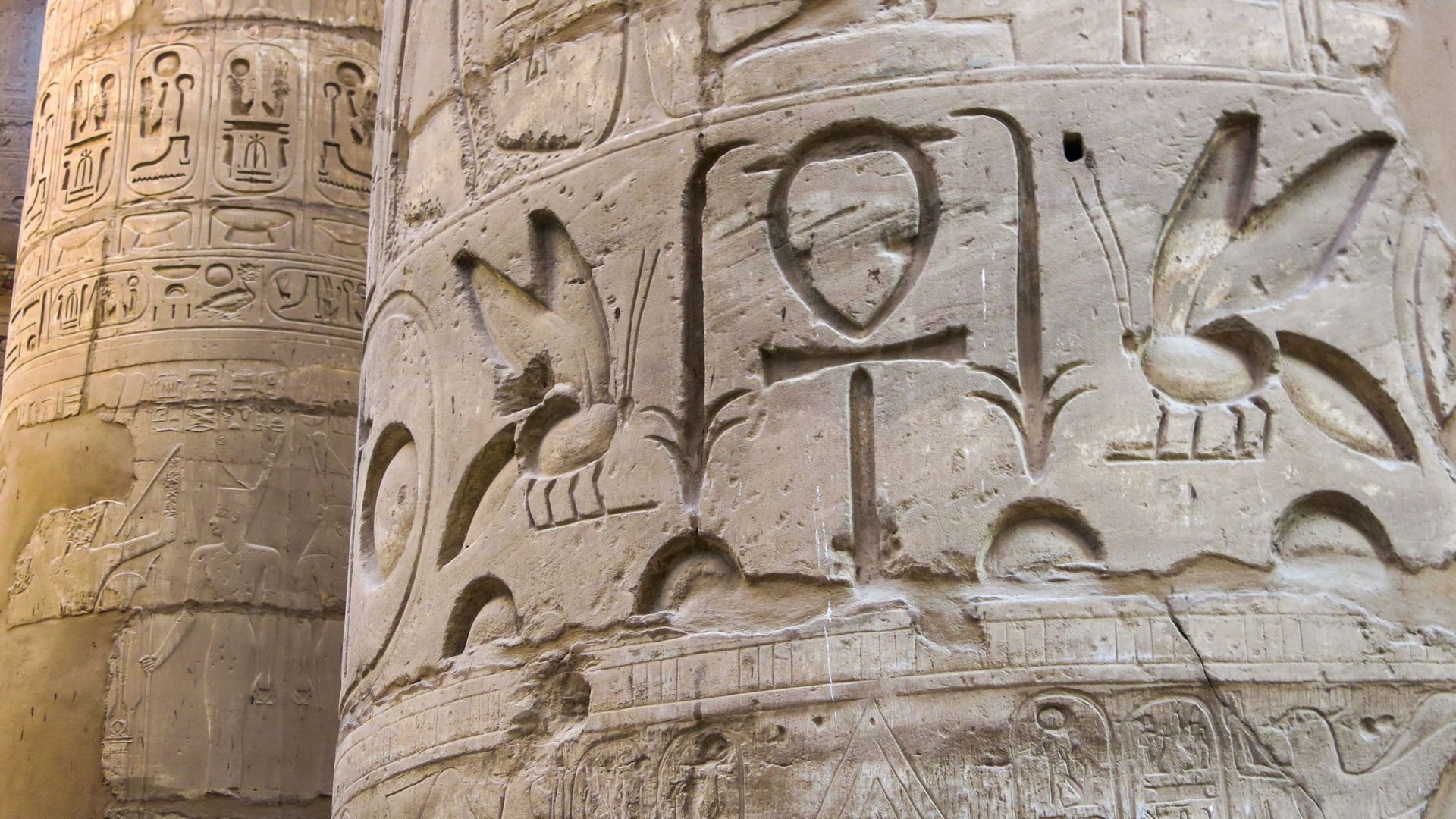 Détail des colonnes du temple de Karnak, à Louxor-Thèbes, en Égypte. Au premier plan, des abeilles, la clé de la vie et la fleur de papyrus. En arrière-plan, on peut voir des détails de reliefs et de hiéroglyphes.