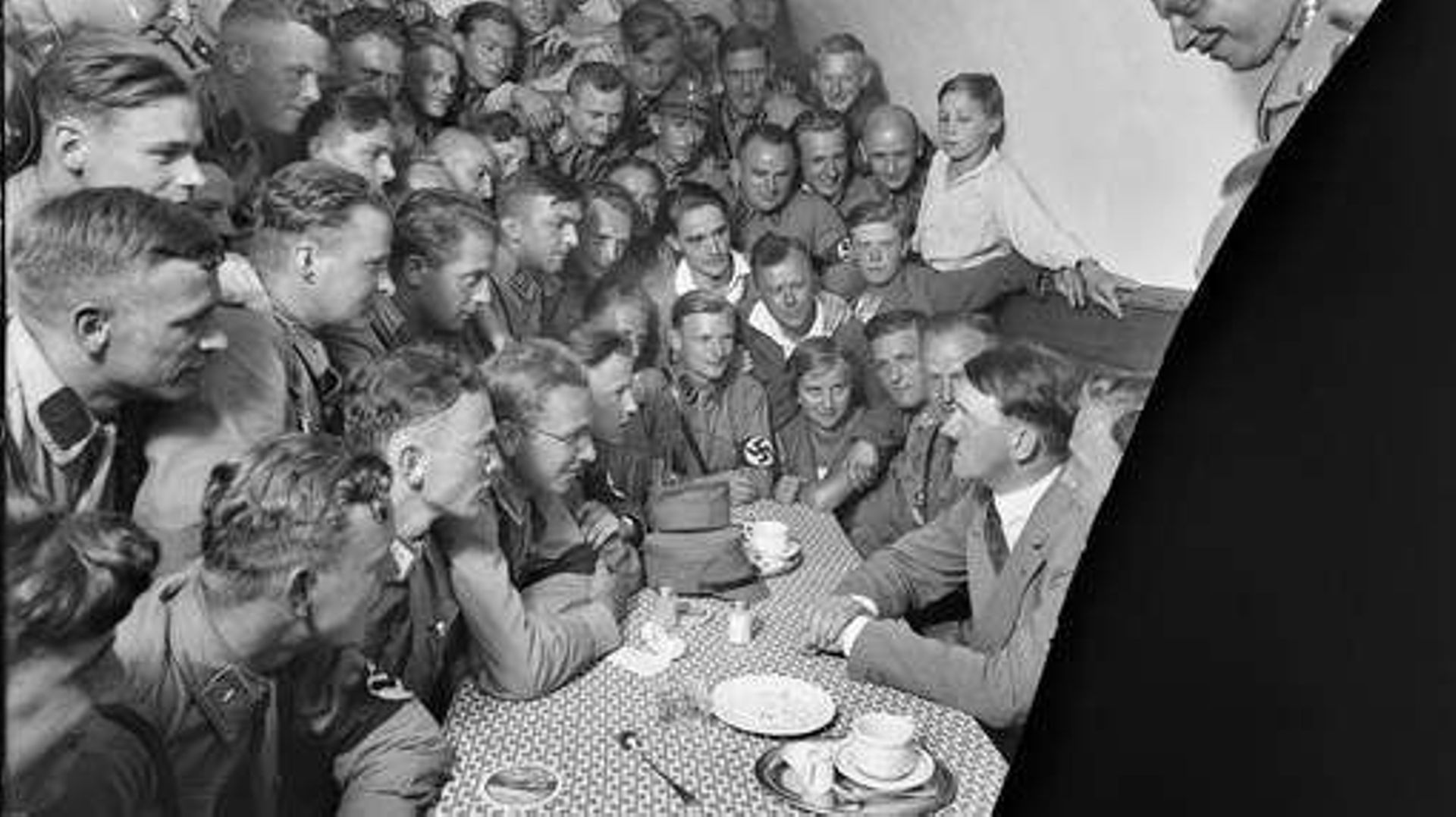 Adolf Hitler, à droite, est assis dans un café avec des admirateurs.