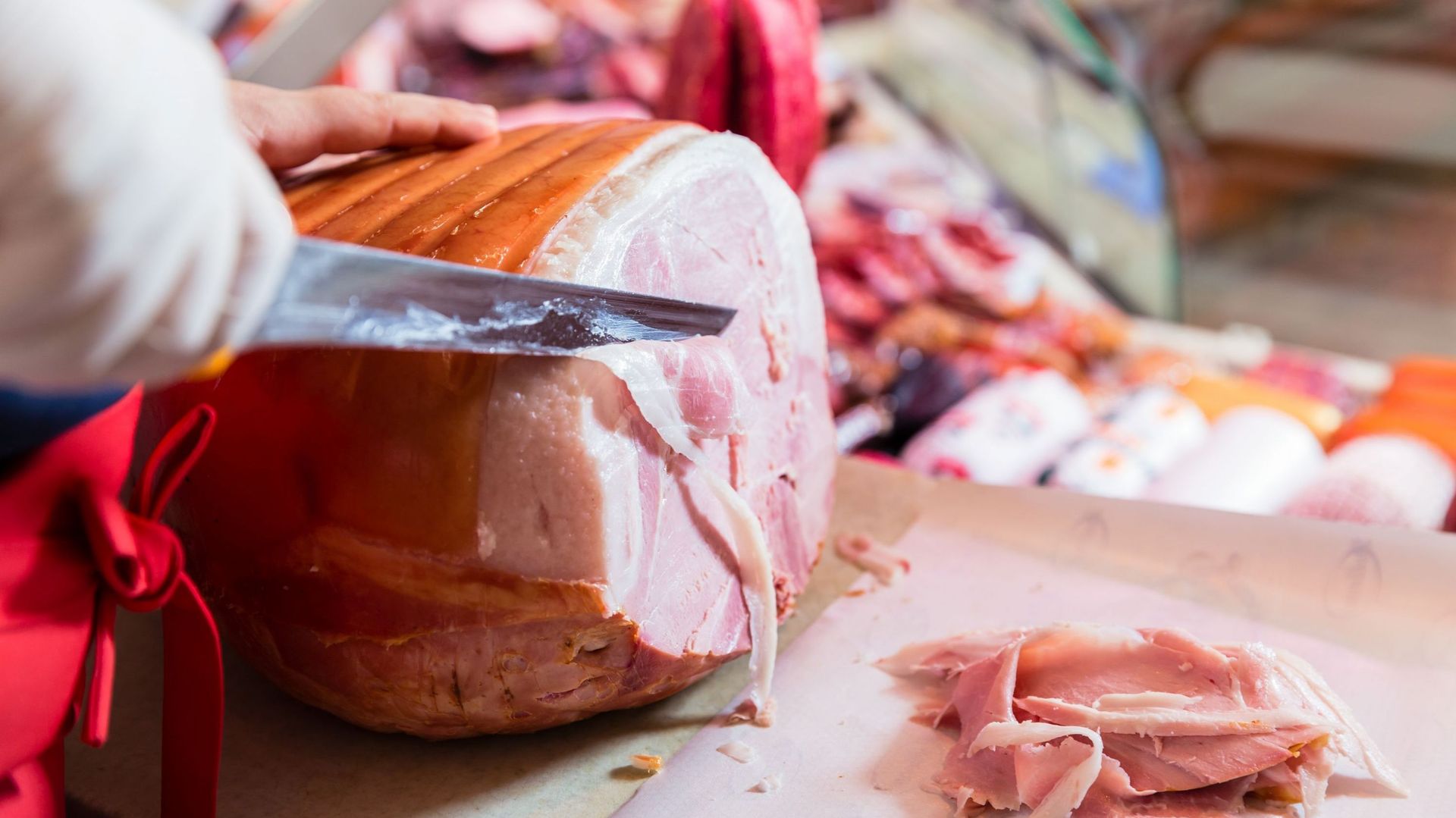 Butcher slicing roasted ham
