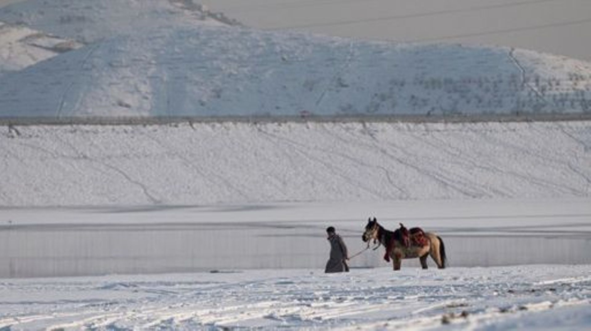 An Afghan youth with his horse walks along the Qargha Lake on the outskirts of Kabul on January 26, 2023. Wakil KOHSAR / AFP