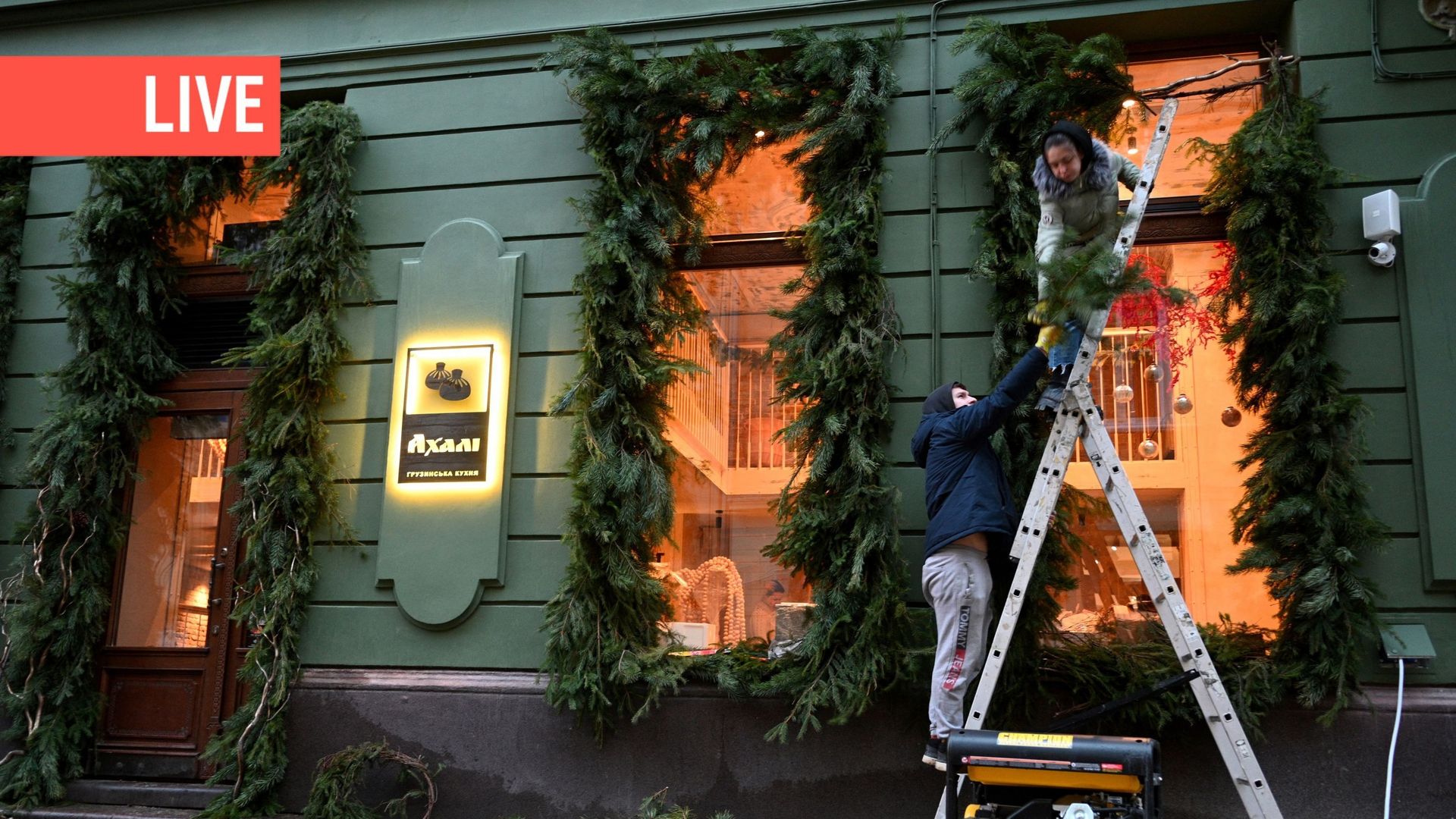 Des employés décorent la fenêtre d’un café dont l’électricité provient d’un générateur situé à l’extérieur, dans le centre de la ville de Lviv, dans l’ouest de l’Ukraine, pendant les heures de coupure de courant, le 22 décembre 2022, alors que la Russie e