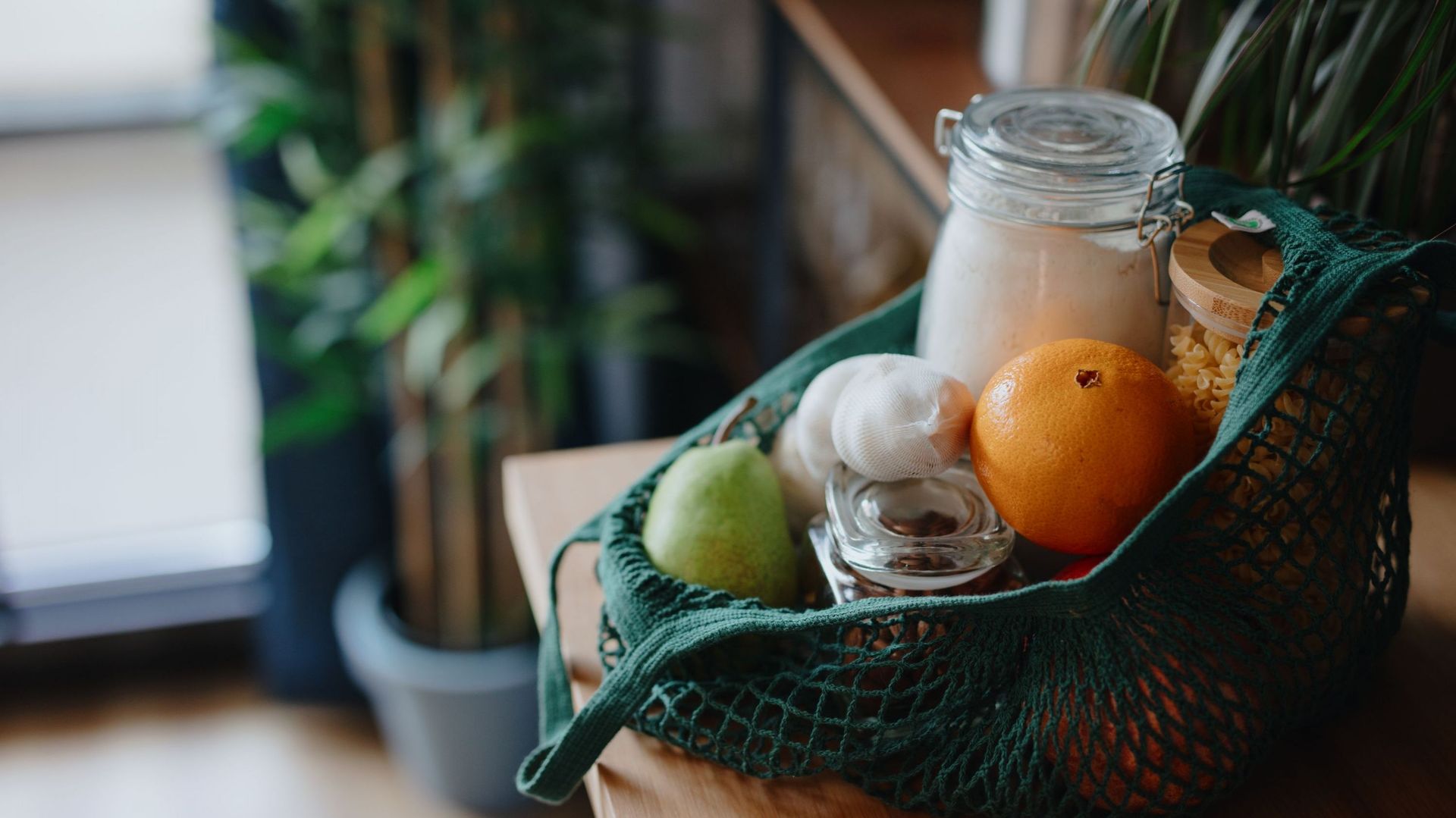 Eco bag on kitchen counter with food in jars and fresh fruits. Zero waste concept