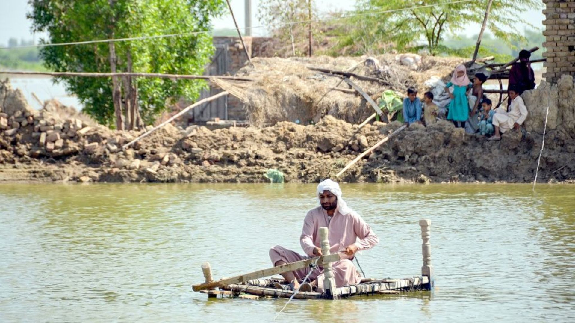 Un homme utilise un radeau de fortune pour traverser les eaux près de sa maison endommagée à Jaffarabad, dans la province du Baloutchistan, le 23 septembre 2022