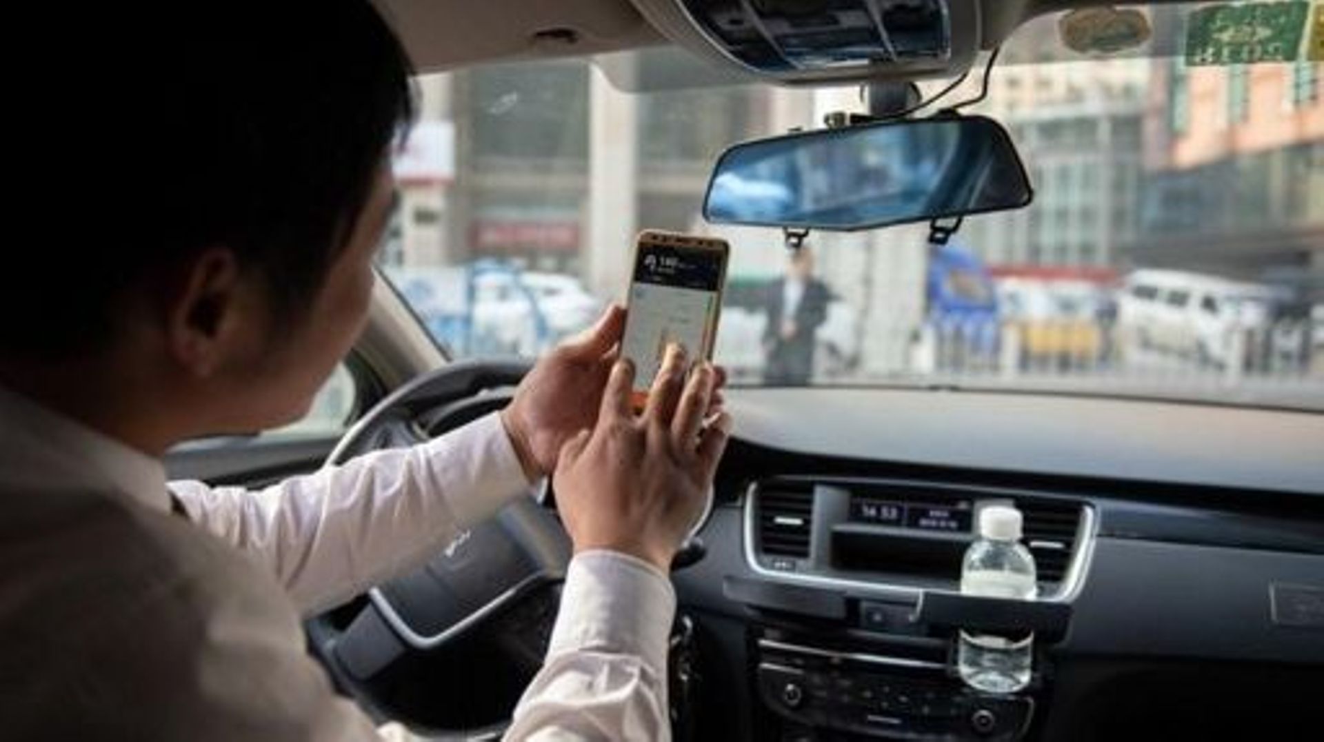 In this picture taken on October 18, 2018, a driver working for ride-sharing company Didi uses his smartphone to choose the best driving route to bring a customer to his destination in Beijing. Didi is a popular taxi and ride-sharing service in China tha