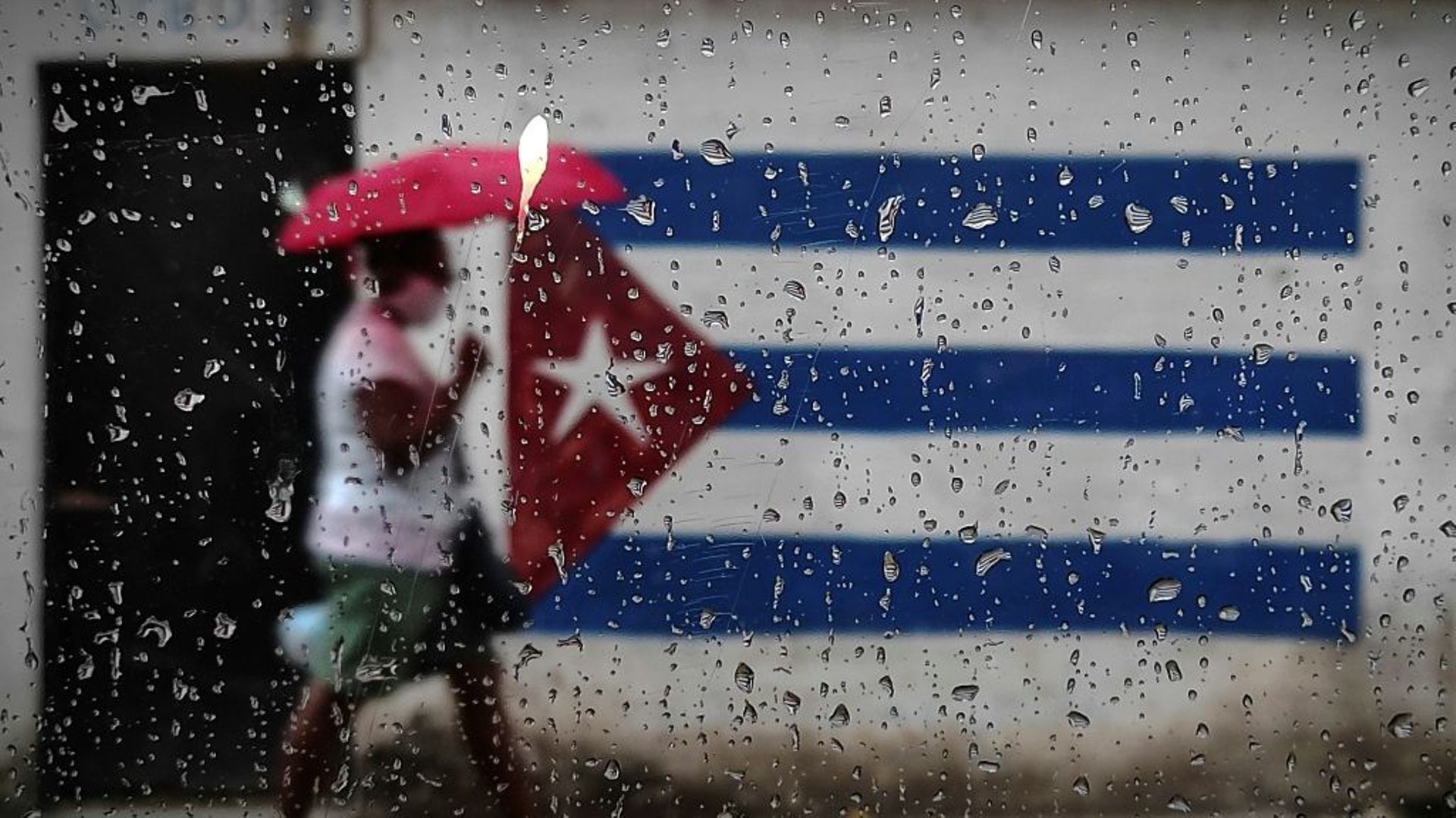 Une femme marche le long d'un mur peint du drapeau cubain à la Havane, le 12 janvier 2021