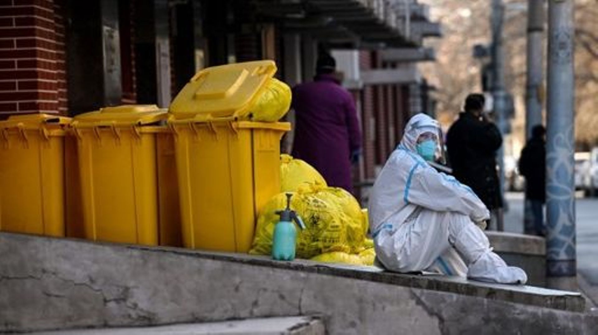 A worker wearing personal protective equipment (PPE) sits next to waste material outside a fever clinic amid the Covid-19 pandemic in Beijing on December 19, 2022.  Noel CELIS / AFP