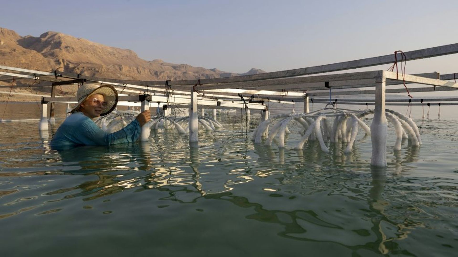 L’artiste israélienne multidisciplinaire Sigalit Landau photographiée à côté de l’une de ses œuvres, immergée dans l’eau salée de la mer Morte à la station balnéaire d’Ein Bokek, le 2 août 2022