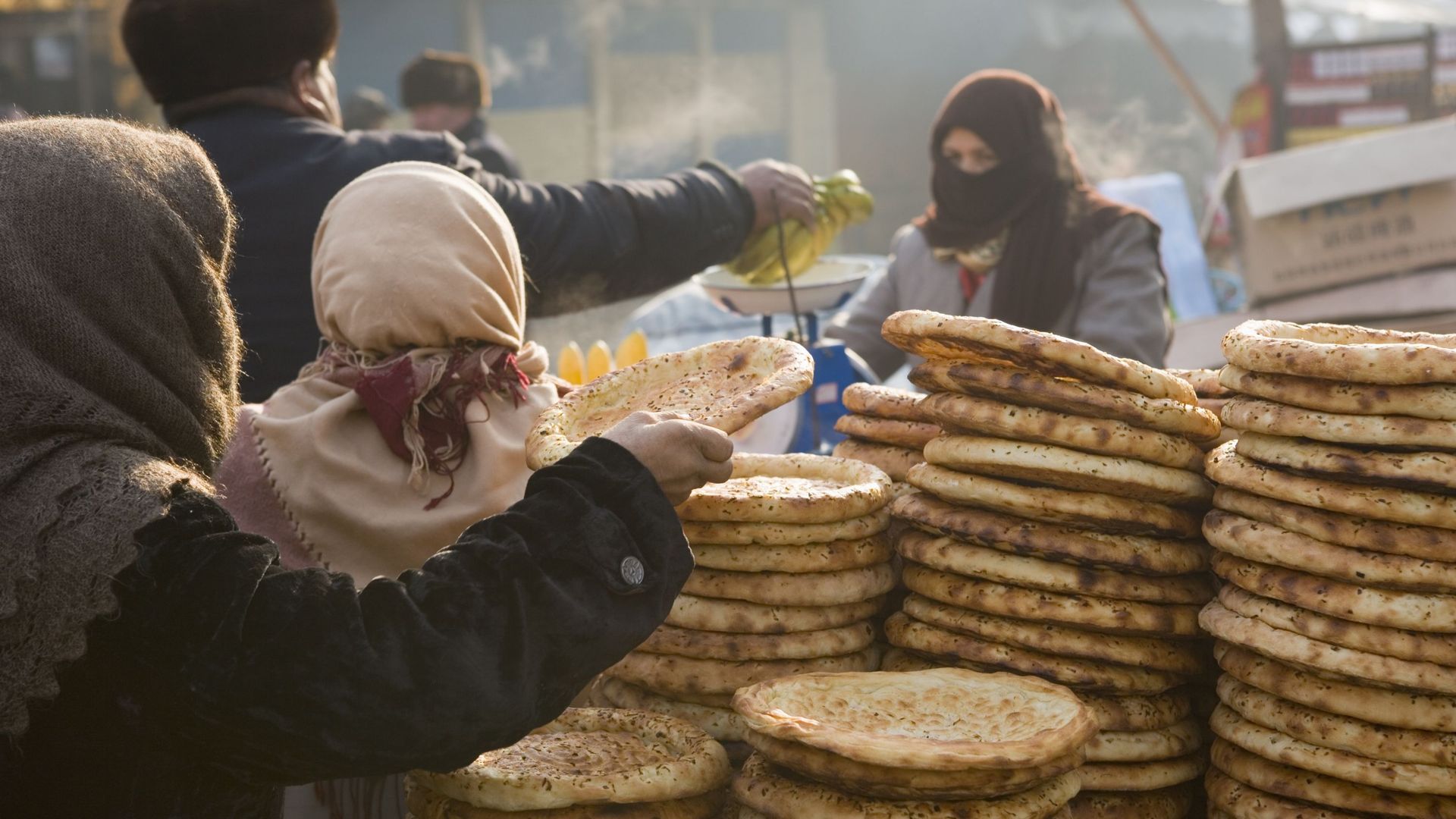 Femme prenant du pain dans une pile au marché à Kashgar, Xinjiang, Chine (illustration)