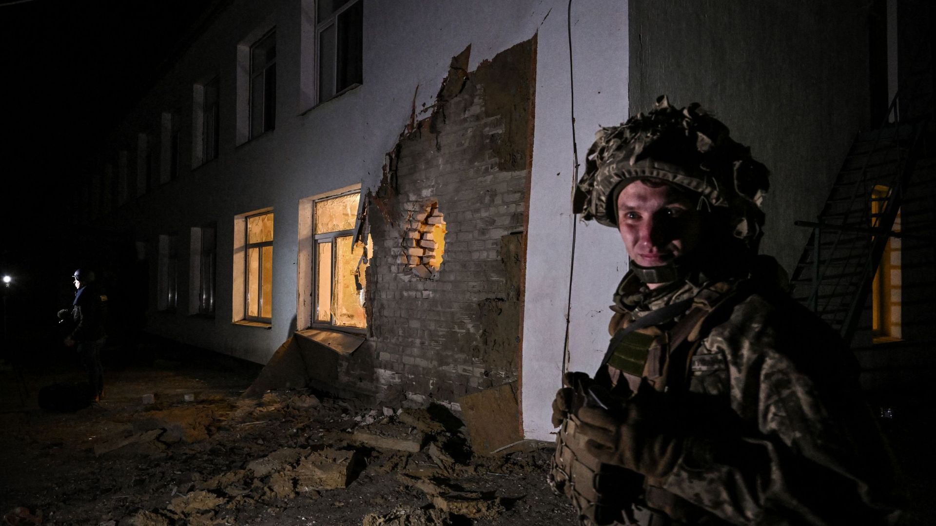 Un soldat ukrainien monte la garde près de débris après le bombardement d'un jardin d'enfants dans la colonie de Stanytsia Luhanska, en Ukraine, le 17 février 2022.