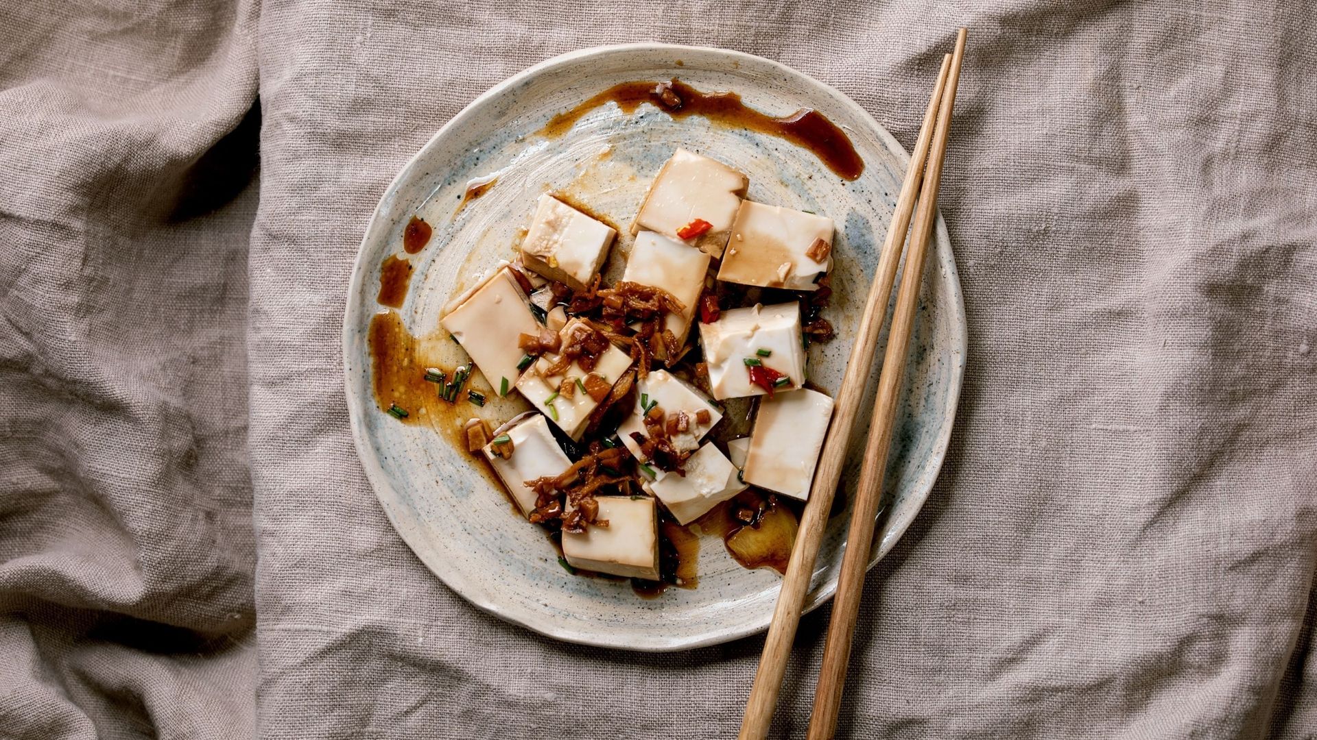 Assiette de tofu et baguettes en bois.