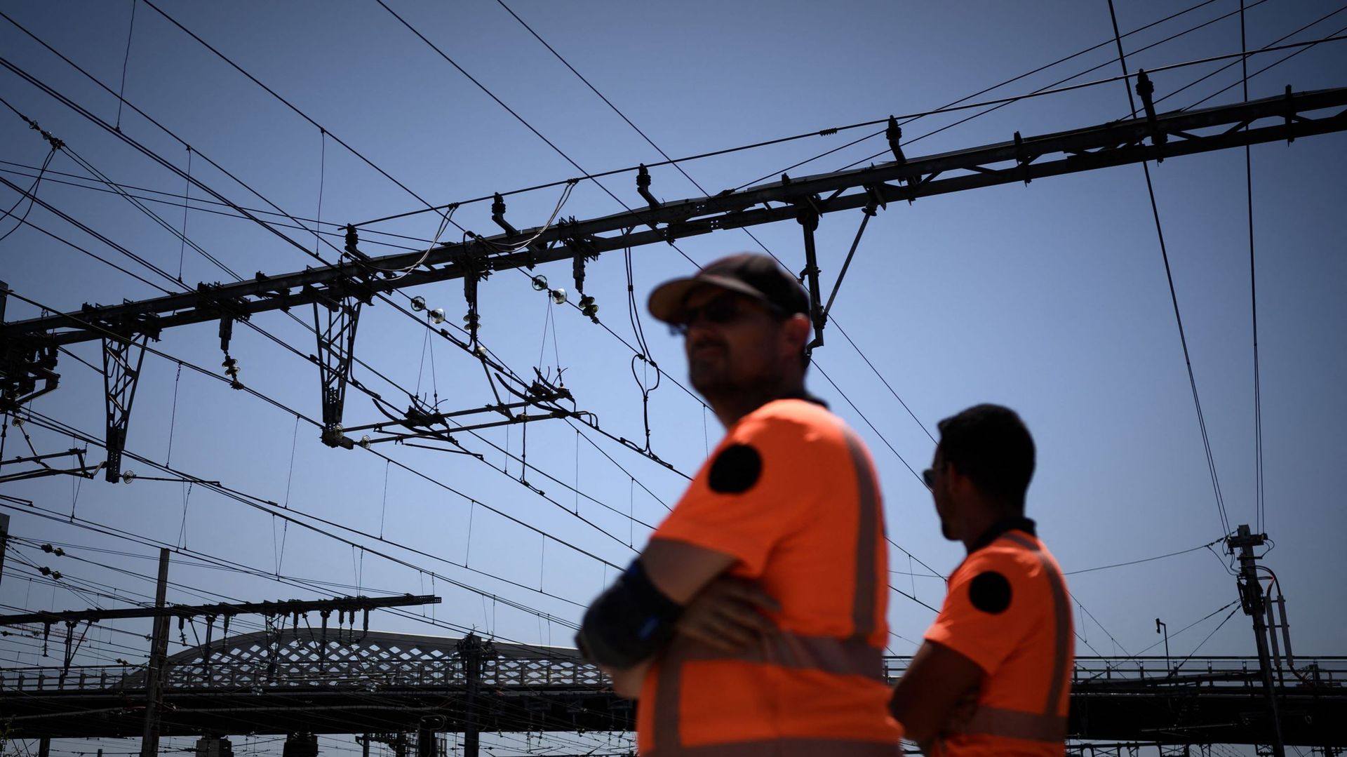 Des employés de la SNCF se tiennent sous des lignes électriques à la gare de Bordeaux, dans le sud-ouest de la France, le 15 juin 2022, alors qu’une vague de chaleur frappe la France.