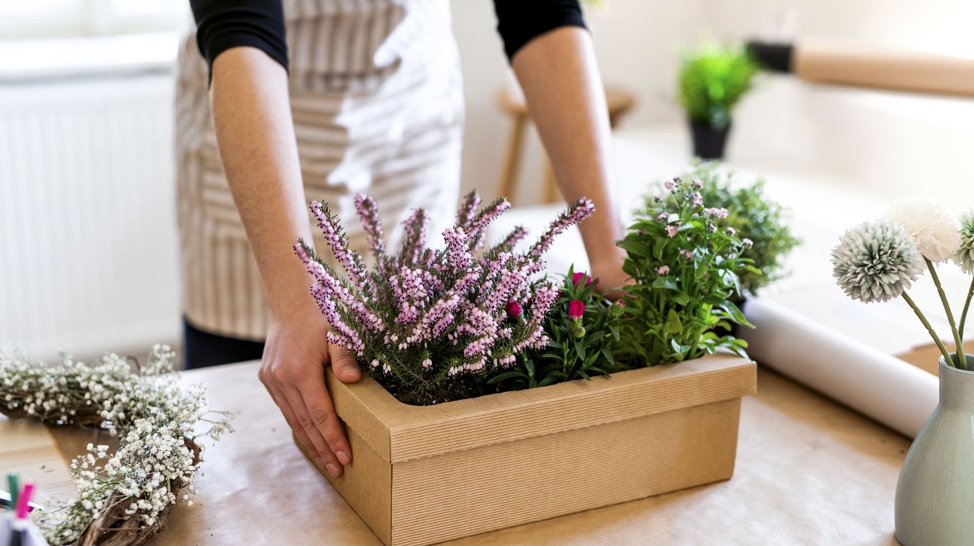 Close-up of woman with flowers inside a cardboard box on table