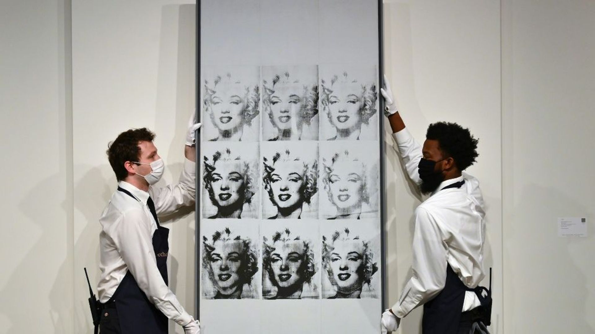 Des employés de Sotheby’s tiennent le célèbre tableau d’Andy Warhol "Nine Marylins", le 5 novembre 2021 à New York