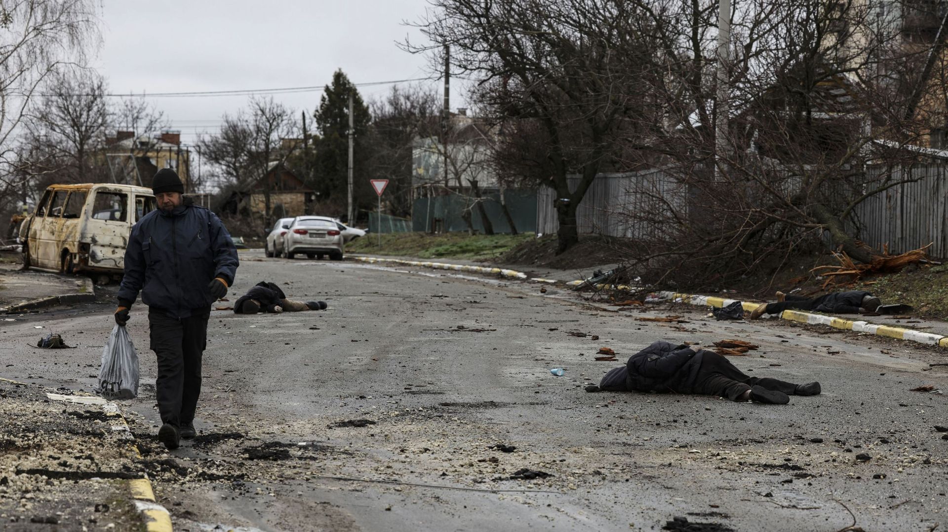 Un homme marche dans une rue avec plusieurs cadavres sur le sol à Boutcha, au nord-ouest de Kiev, alors que l’Ukraine déclare que les forces russes effectuent une "retraite rapide" des zones du nord autour de Kiev et de la ville de Tchernigiv, le 2 avril