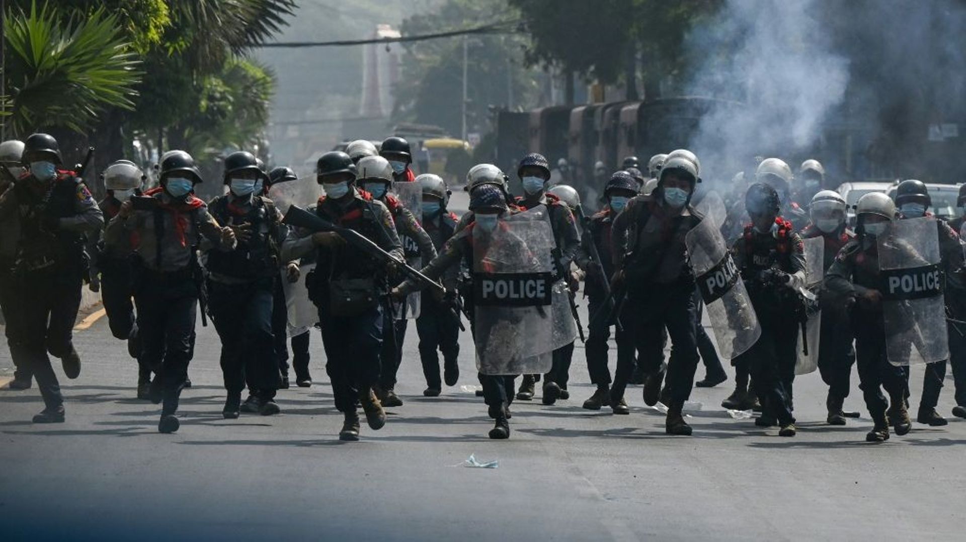 Des policiers courent vers des manifestants rassemblés contre le coup d'Etat militaire, le 27 février 2021 à Rangoun, en Birmanie