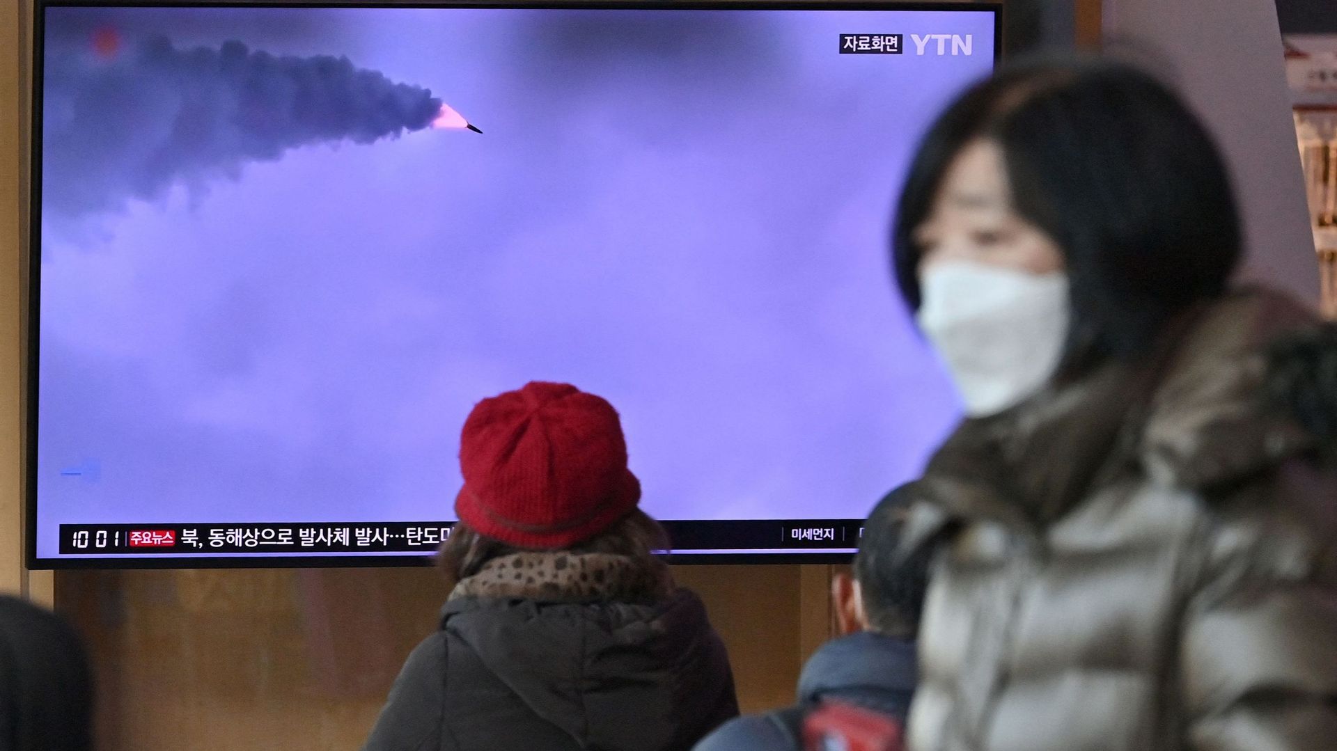 Des personnes regardent un écran de télévision montrant un journal télévisé avec des images d'archives d'un essai de missile nord-coréen, dans une gare de Séoul, le 5 mars 2022.