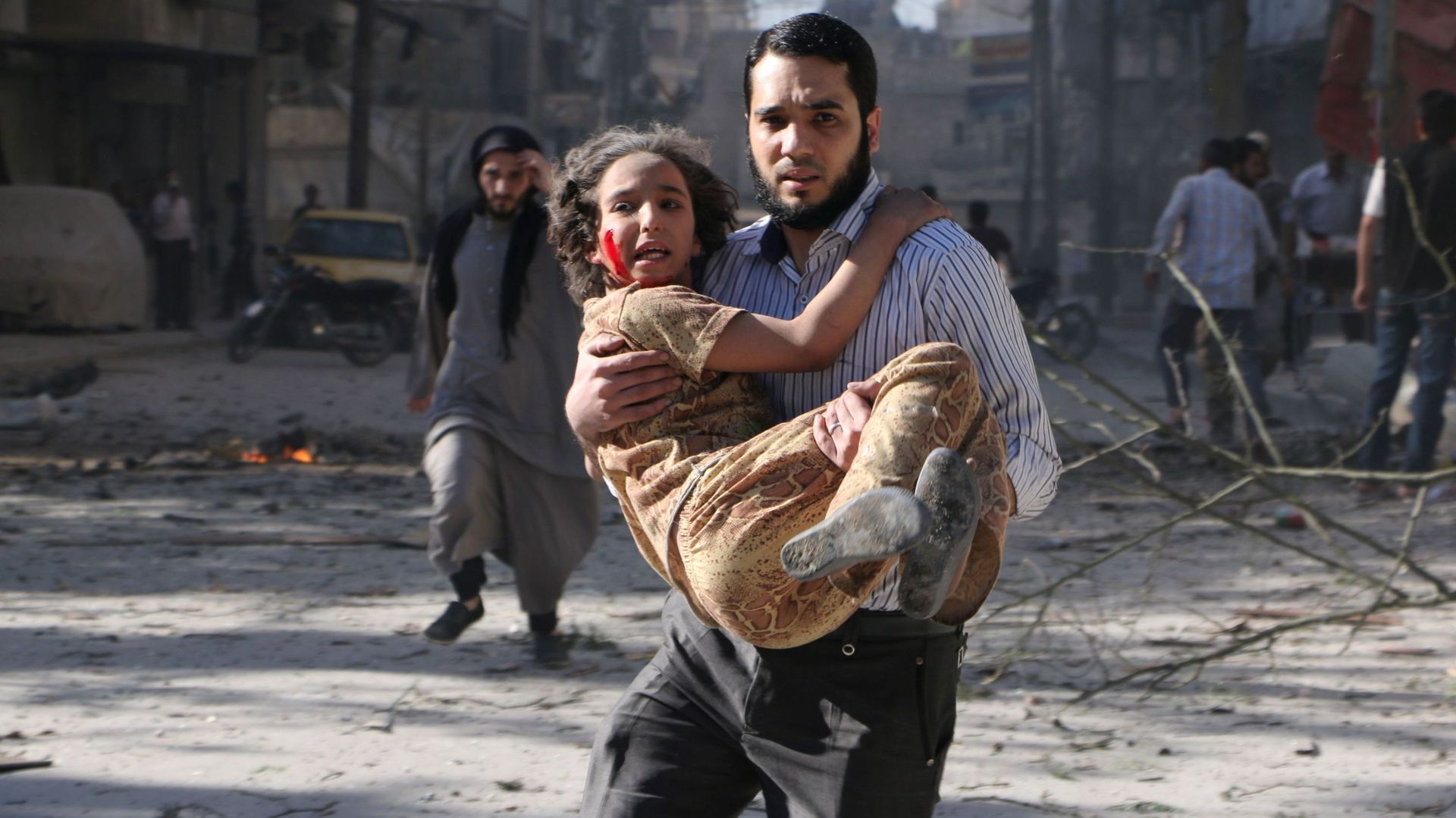 Un homme portant une fillette après un bombardement aérien, dans la banlieue d'Alep, ce dimanche
