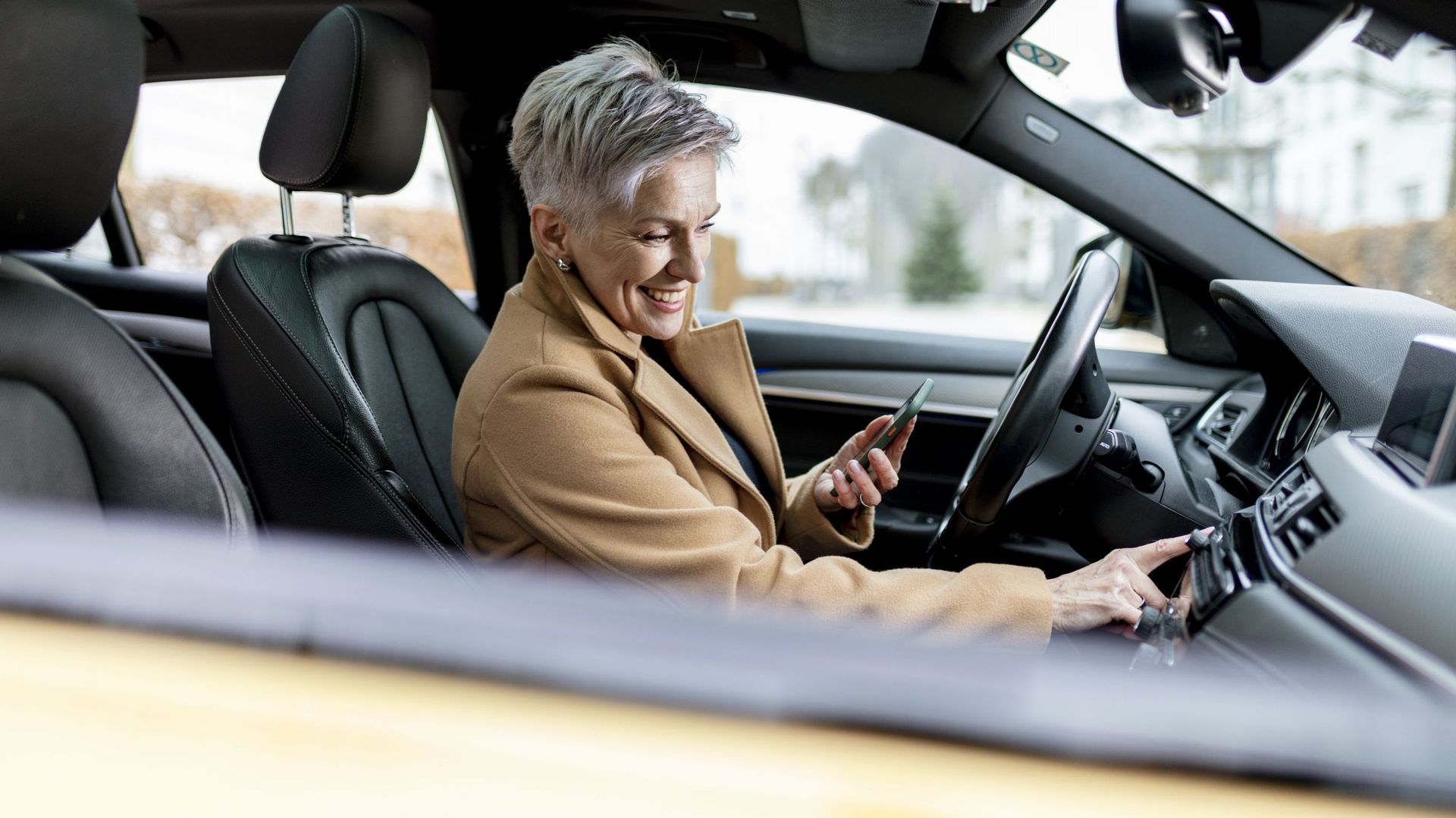 Active bestager woman using smart phone to start a sharing car.