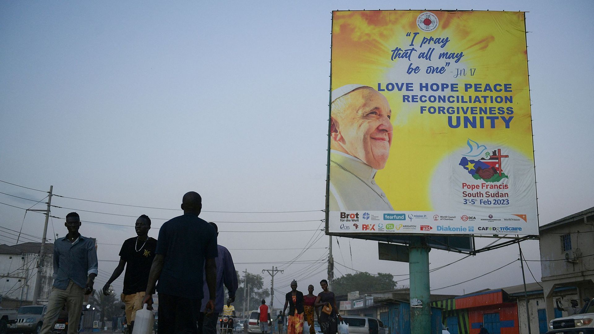 Des piétons passent devant une bannière montrant le portrait du pape François alors que les préparatifs se poursuivent en vue de sa visite à Juba, le 31 janvier 2023.