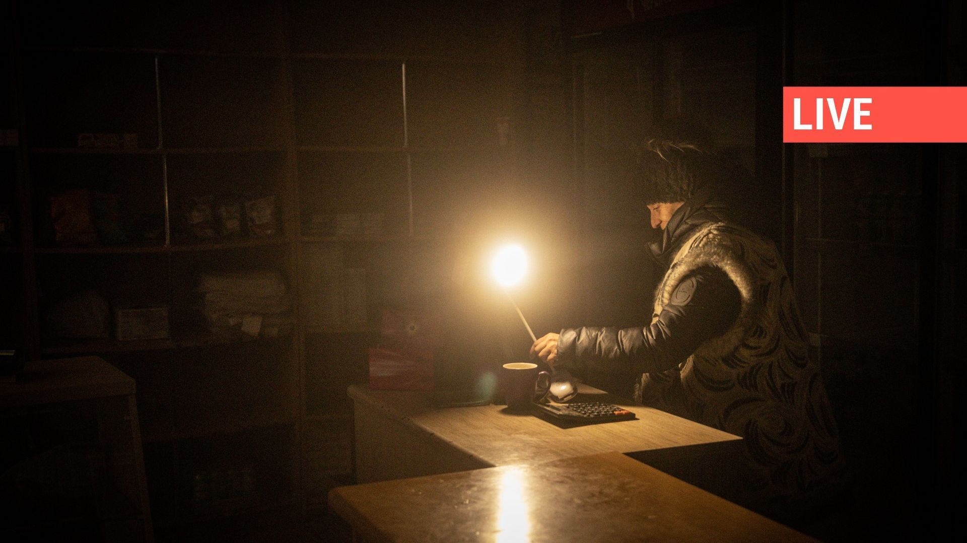 Une femme travaille à la lumière d'une lampe dans l'une des seules épiceries ouvertes le 13 décembre 2022 à Bakhmut, en Ukraine. 