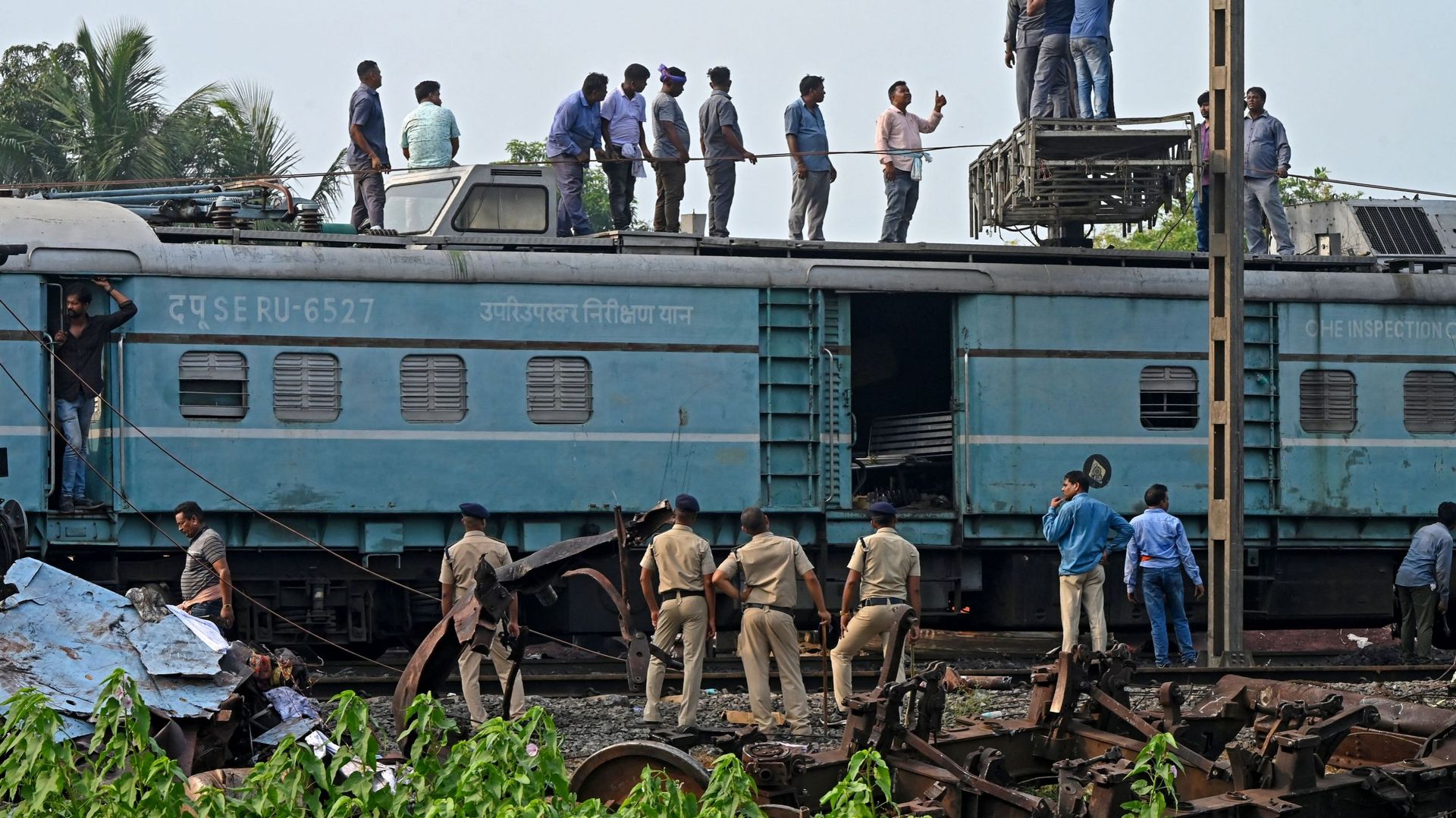 Des policiers inspectent les wagons accidentés lors d'une collision entre trois trains près de Balasore, dans l'État indien d'Odisha, le 4 juin 2023.