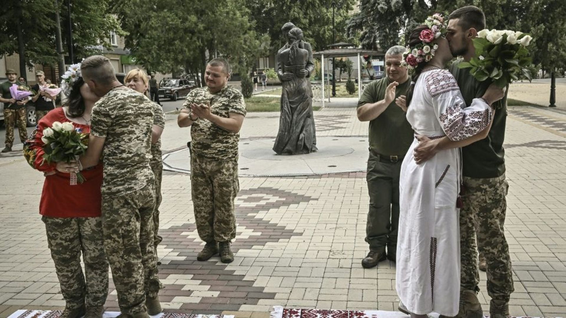 Des couples de militaires ukrainiens, Kristina et Vitali Orlich (à droite), ainsi que Kristina Liouta et Volodymyr Mikhalchouk (à gauche), s’embrassent après avoir été mariés dans la ville de Droujkivka, dans l’est de l’Ukraine, le 12 juin 2022