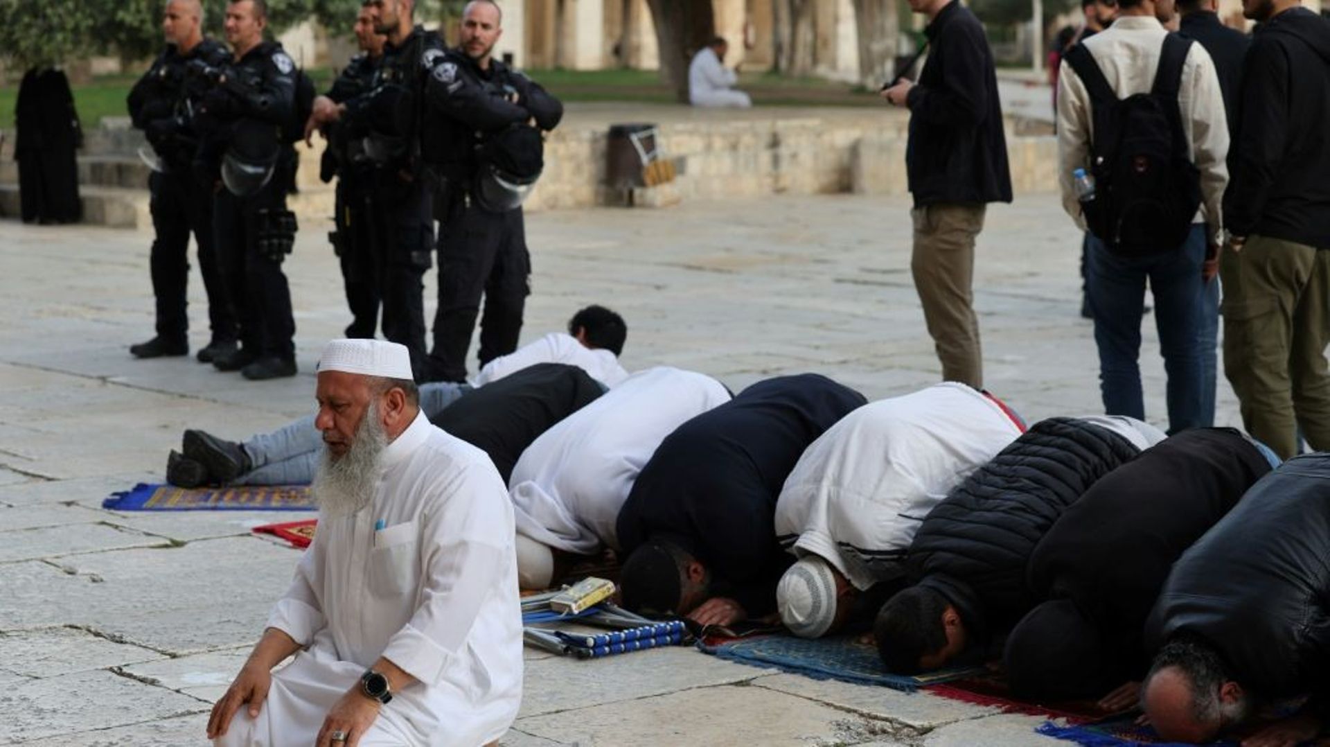 Des fidèles musulmans prient pendant que des soldats israéliens escortent des visiteurs juifs sur l’esplanade des mosquées, le 9 avril 2023 à Jérusalem.