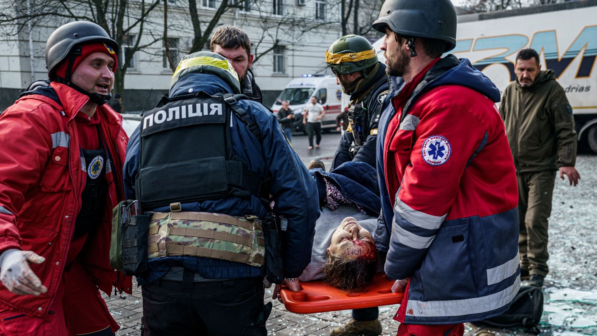 Des sauveteurs transportent sur une civière une femme blessée à la suite d'un bombardement russe sur la ville ukrainienne de Kherson, le 24 décembre 2022