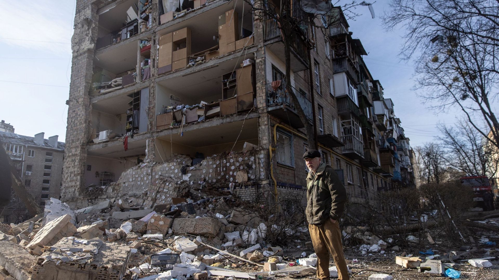 Un homme se tient au milieu de débris devant un complexe d'appartements résidentiels qui a été fortement endommagé par une attaque russe, le 18 mars 2022 à Kiev, en Ukraine.