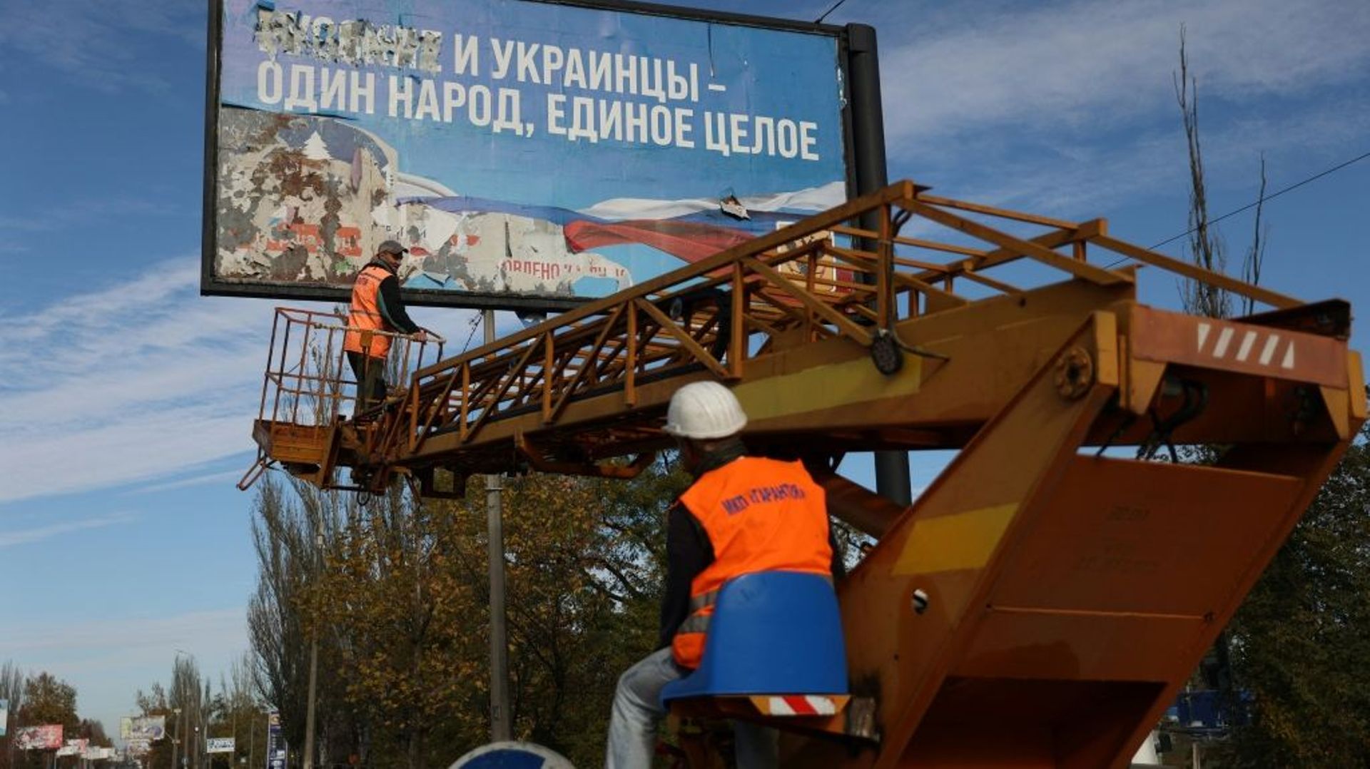 Des employés retirent une pancarte datant de l’occupation russe et proclamant que Russes et Ukrainiens forment un seul peuple, à Kherson dans le Sud de l’Ukraine le 14 novembre 2022.
