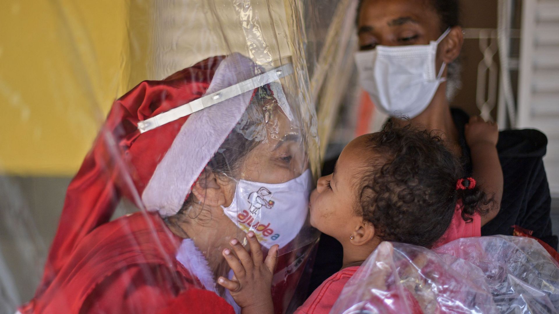 Une photo prise à Noël au Brésil, entre une volontaire et une enfant précarisée séparée par un rideau en plastique, coronavirus oblige.