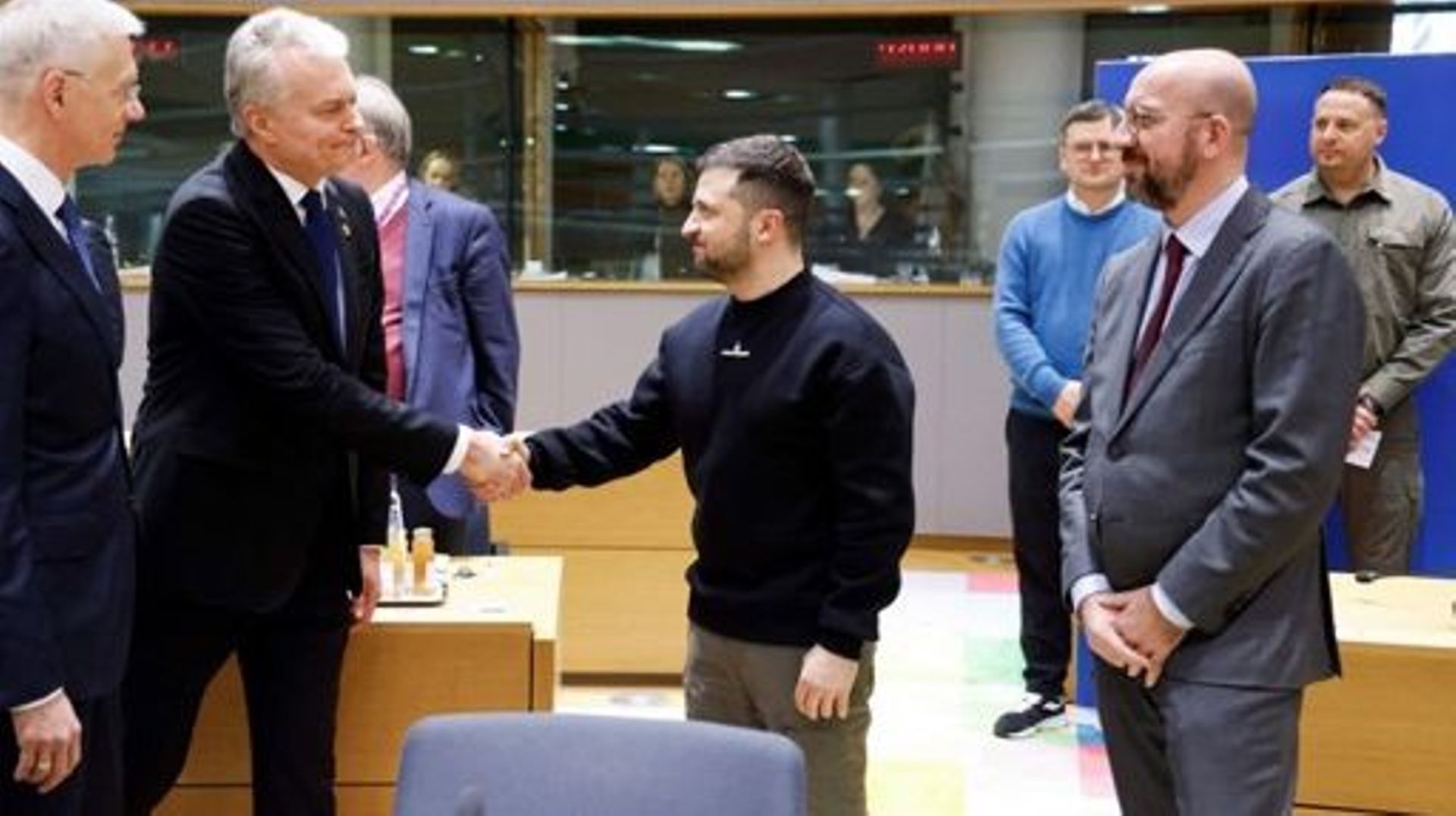Le président ukrainien, Volodymyr Zelensky (C), serre la main du président lituanien, Gitanas Nauseda, sous le regard du Premier ministre letton, Krisjanis Karins (L), avant une table ronde organisée dans le cadre d’un sommet européen à Bruxelles, le 9 fé