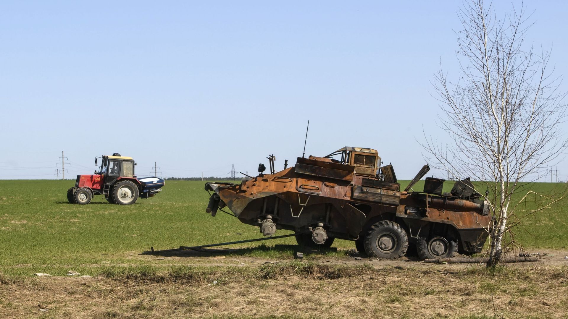 Un tracteur travaille sur un champ agricole près d'un char militaire russe détruit près de Kiev en Ukraine, le 15 avril 2022. 