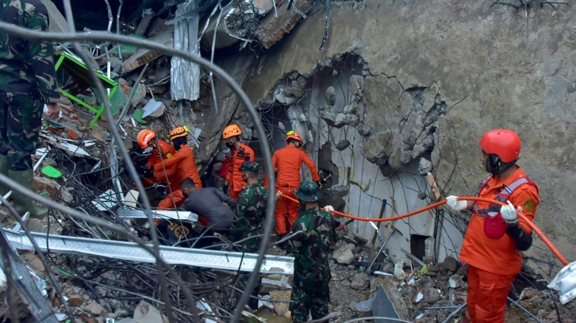 Des sauveteurs recherchent des survivants dans les ruines d'un bâtiment, à Mamuju, sur l'île des Célèbes en Indonésie, le 15 janvier 2021