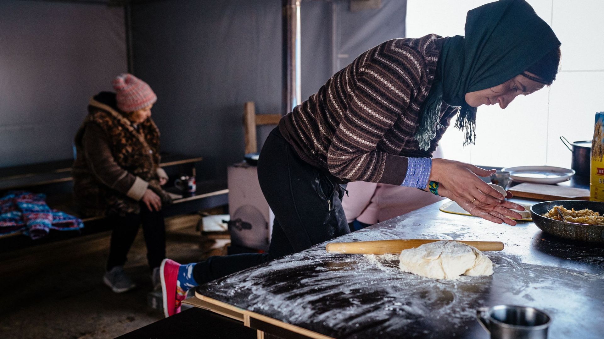 Une habitante, qui vit dans une ville modulaire après la destruction de sa maison, cuisine dans une tente où elle peut se réchauffer à Borodyanka, près de Kiev, le 4 décembre 2022, en pleine invasion russe de l’Ukraine. Avec des températures en dessous de
