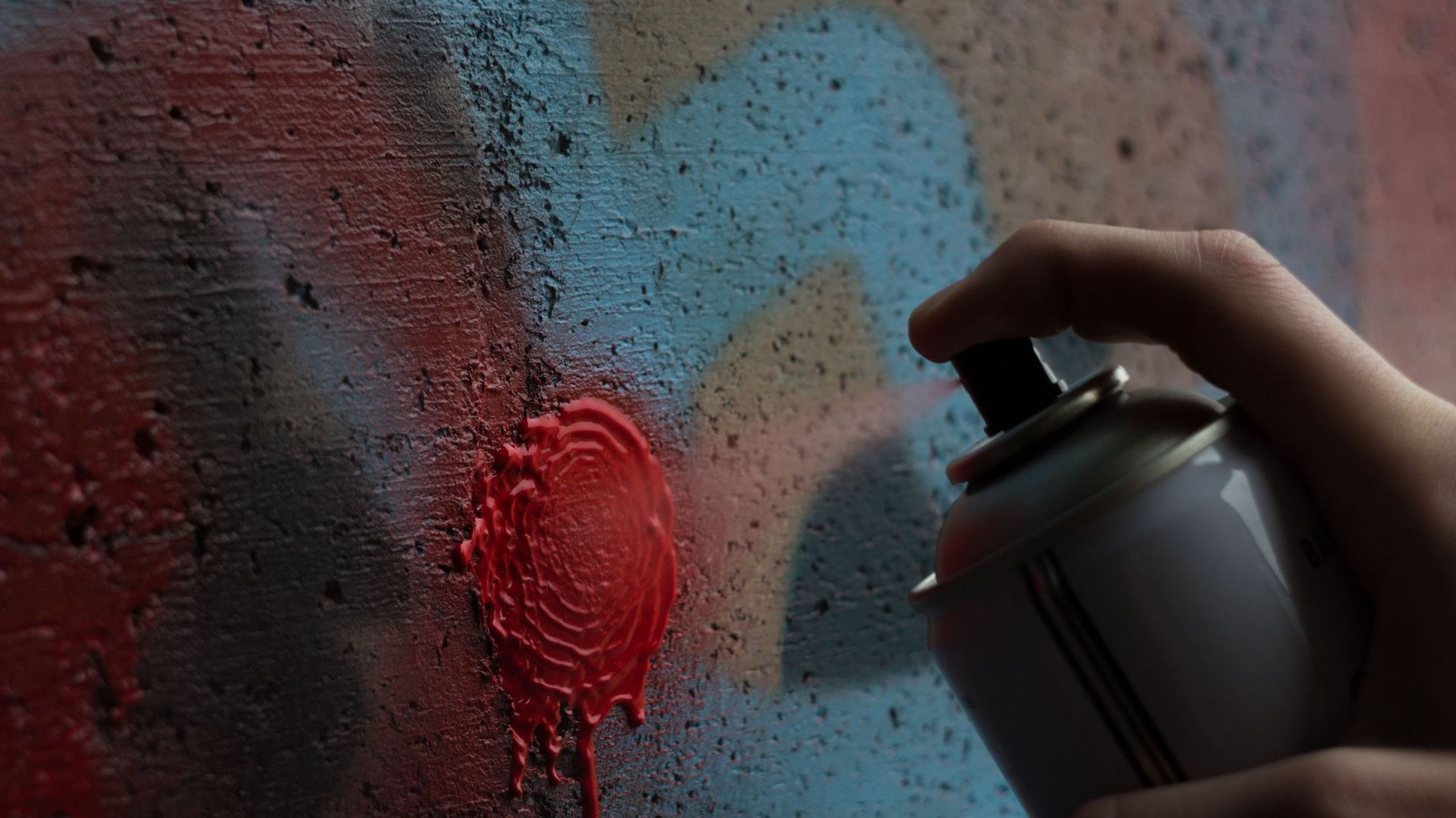 Cropped Image Of Hand Spraying Paint On Wall