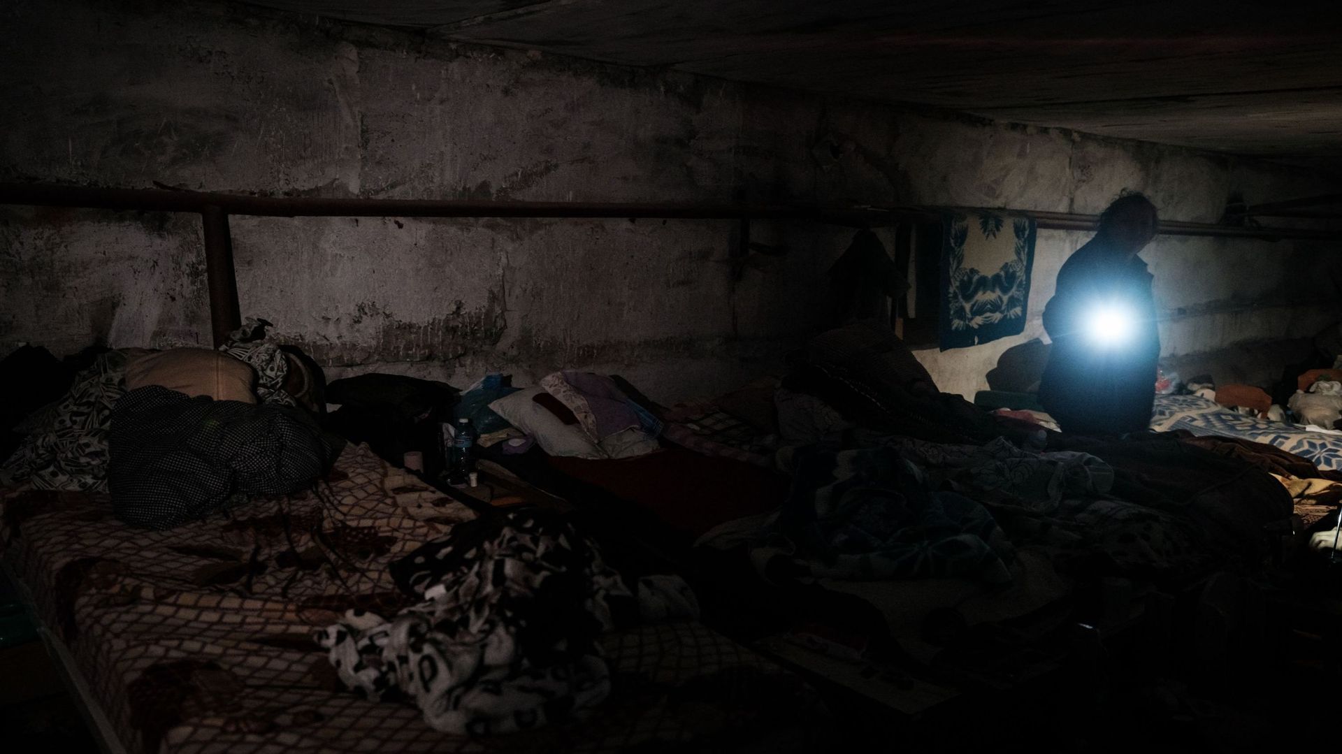 Natalia Georgiyevna, 70 ans, utilise une torche alors qu’elle se tient dans l’abri de fortune du sous-sol d’un jardin d’enfants, où elle vit avec six autres personnes depuis plus de deux mois, à Lyssytchansk, en Ukraine orientale, le 14 mai 2022.