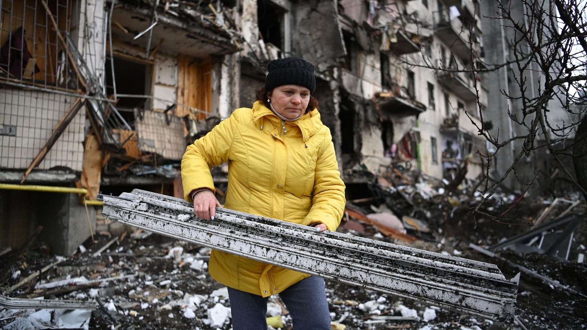 Une femme débarrasse les débris d'un bâtiment résidentiel endommagé dans la rue Koshytsa, une banlieue de la capitale ukrainienne Kiev, où un obus militaire aurait frappé, le 25 février 2022.