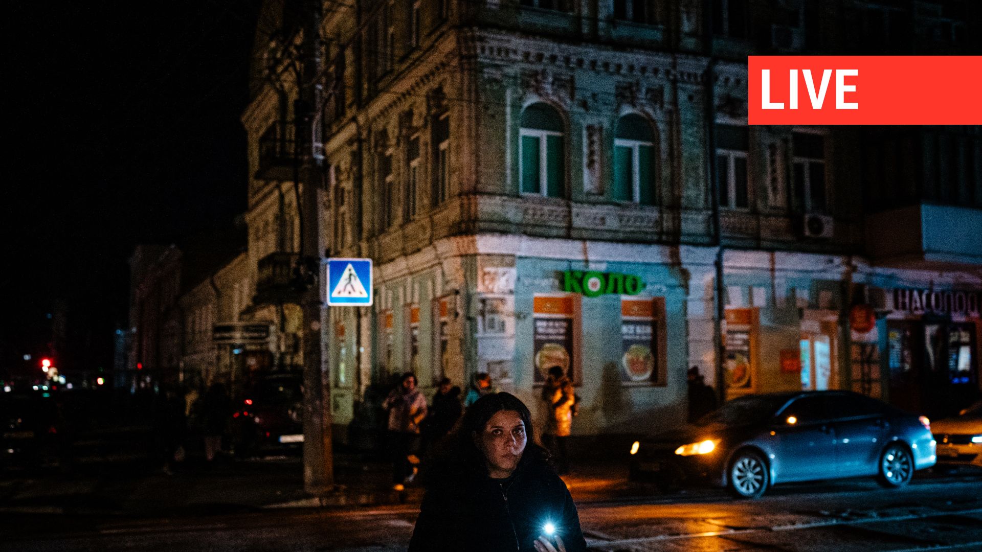Une habitante utilise une lampe de poche alors qu'elle marche dans la rue pendant une panne partielle à Kiev, le 14 décembre 2022.