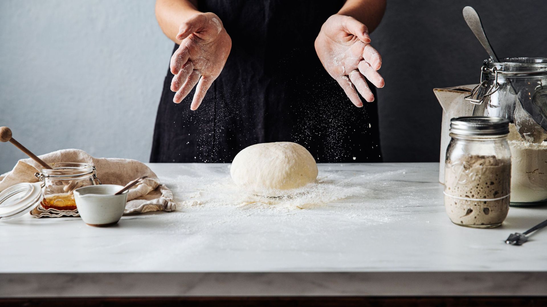 Woman throwing dough on flour over marble counter
