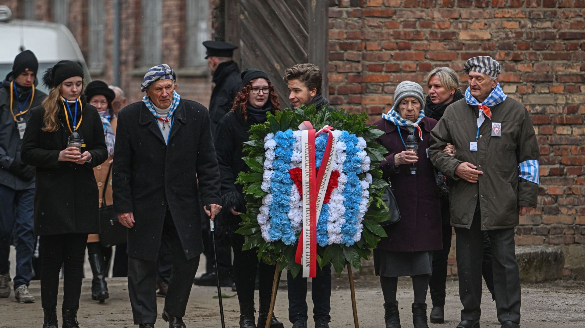 Des survivants du camp de concentration d’Auschwitz et des familles arrivent pour déposer des couronnes en hommage aux victimes du régime nazi près du mur de la mort lors de la journée de commémoration de l’Holocauste sur l’ancien site d’Auschwitz I, le 2