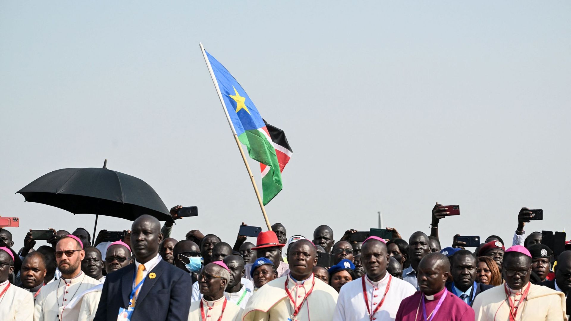 Un homme brandit un drapeau sud-soudanais alors que le pape François arrive à l’aéroport international de Juba, au Sud-Soudan, le 3 février 2023.