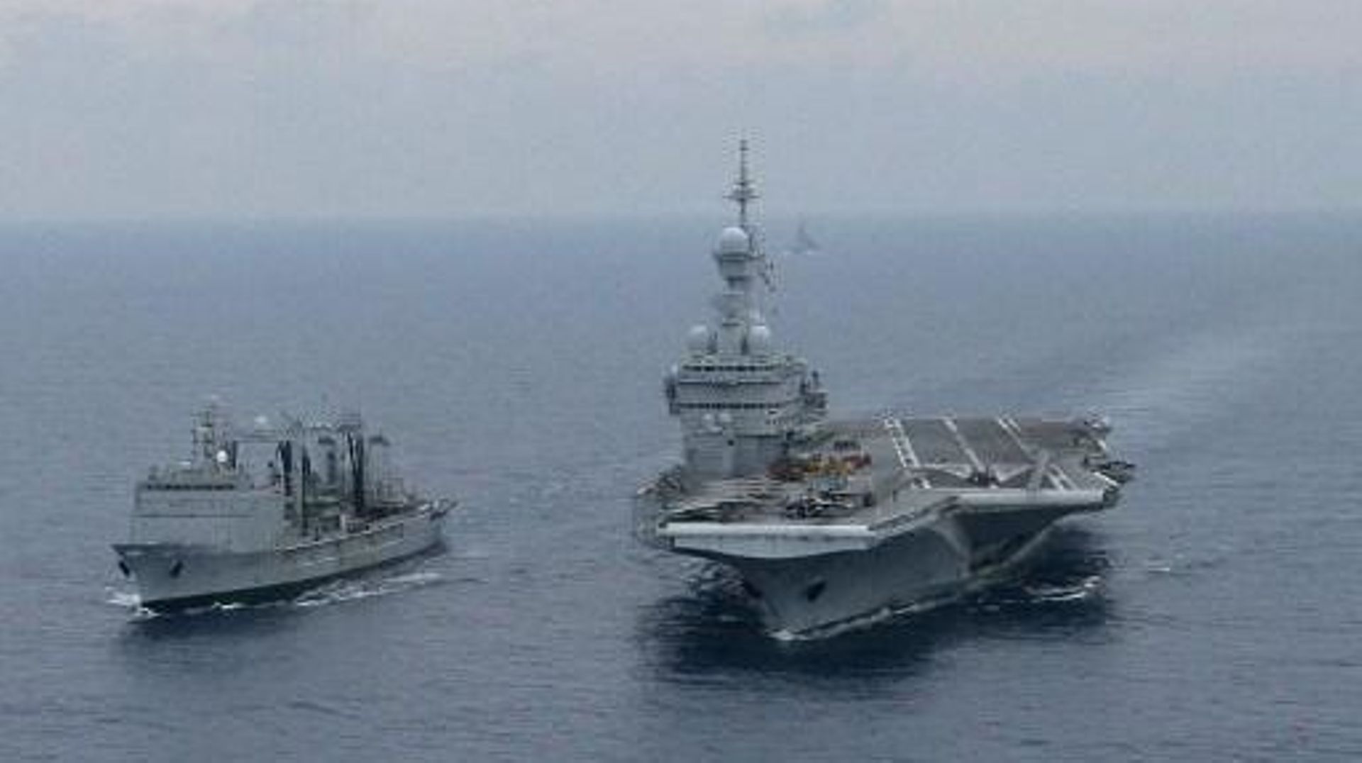 This aerial view taken from a Puma helicopter on April 22, 2011 shows the Charles de Gaulle aircraft carrier (R) and the French Navy auxiliary Ship Meuse (L) in the Mediteranean sea, as part of the military operations of the NATO coalition in Libya.  NATO