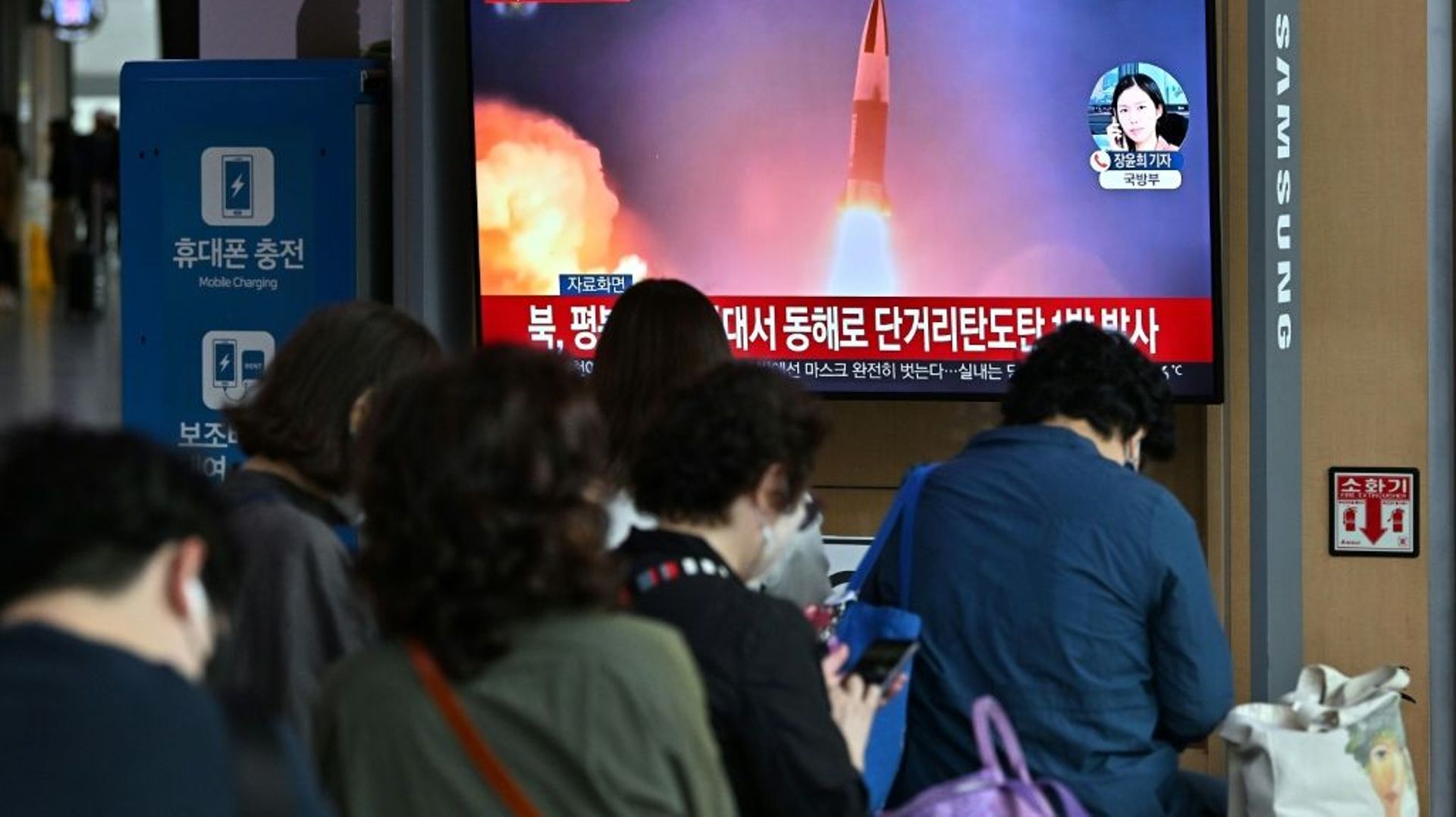 Des voyageurs devant un écran de télévision montrant des images d’archives d’un test de missile nord-coréen, dans une gare de Séoul, le 25 septembre 2022