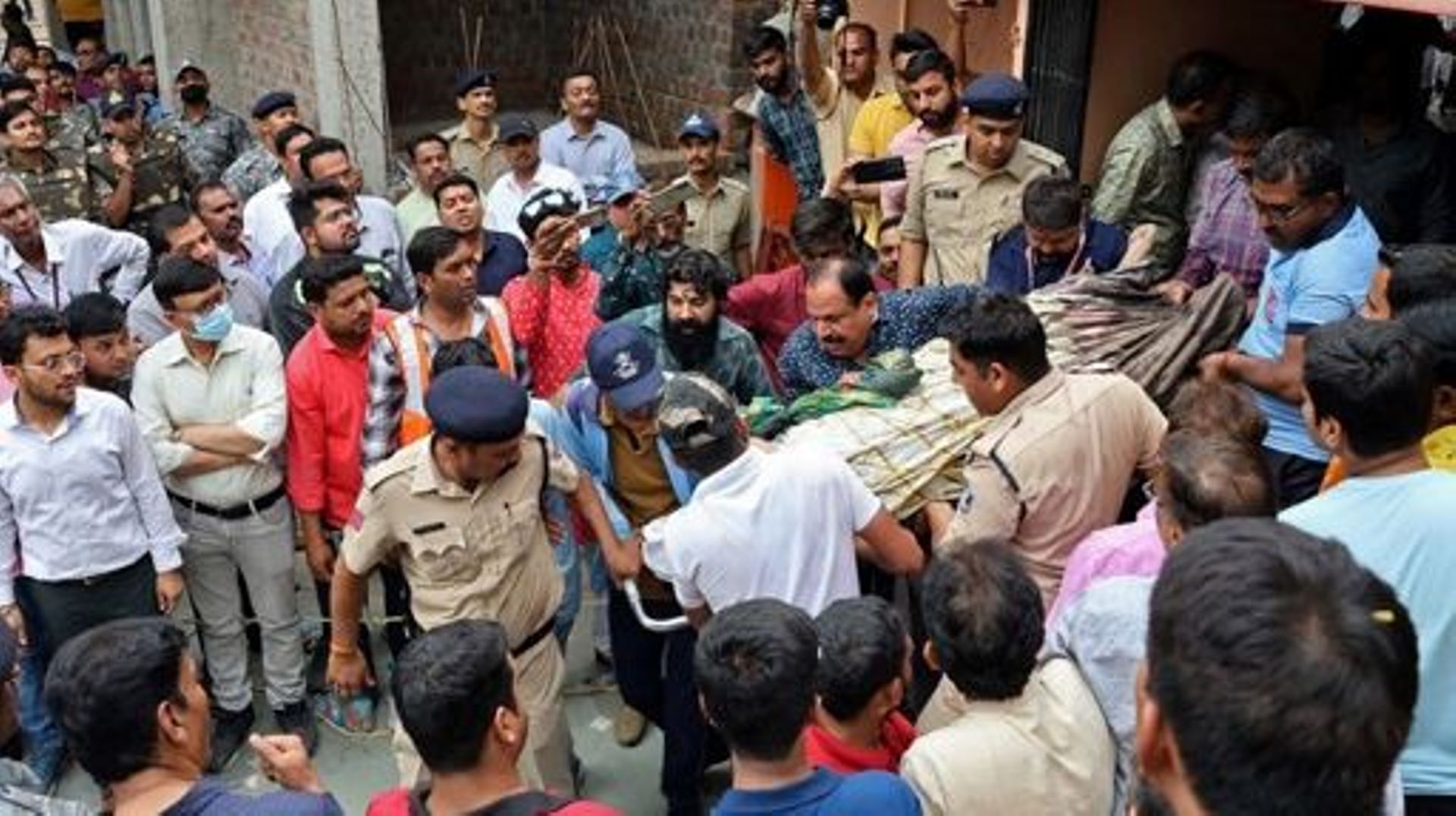 Rescue and security personnel carry a devotee on a stretcher who was injured after the floor covering a stepwell collapsed at a temple in Indore on March 30, 2023. At least 13 devotees were killed and more than a dozen rescued on March 30 after they fell 