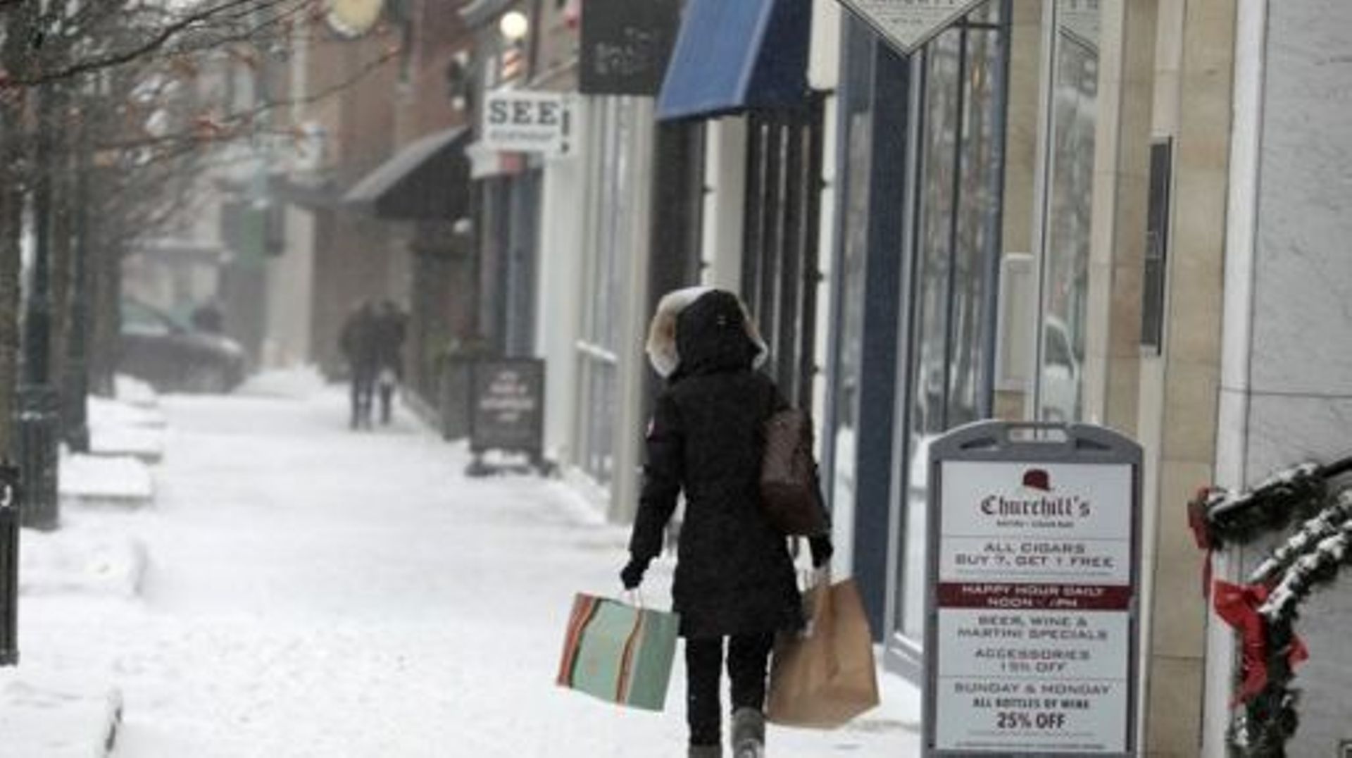 Des acheteurs bravent le mauvais temps dans le centre-ville de Birmingham, Michigan, le 23 décembre 2022. Une tempête hivernale historique et brutale a placé quelque 240 millions d'Américains sous le coup d'alertes météorologiques vendredi, alors que les 