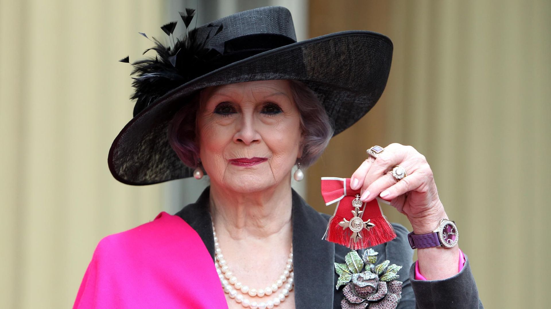 April Ashley tient sa médaille de membre de l'Empire britannique (MBE) qui lui a été remise par la reine Elizabeth II lors d'une cérémonie d'investiture au palais de Buckingham le 13 décembre 2012 à Londres, en Angleterre.